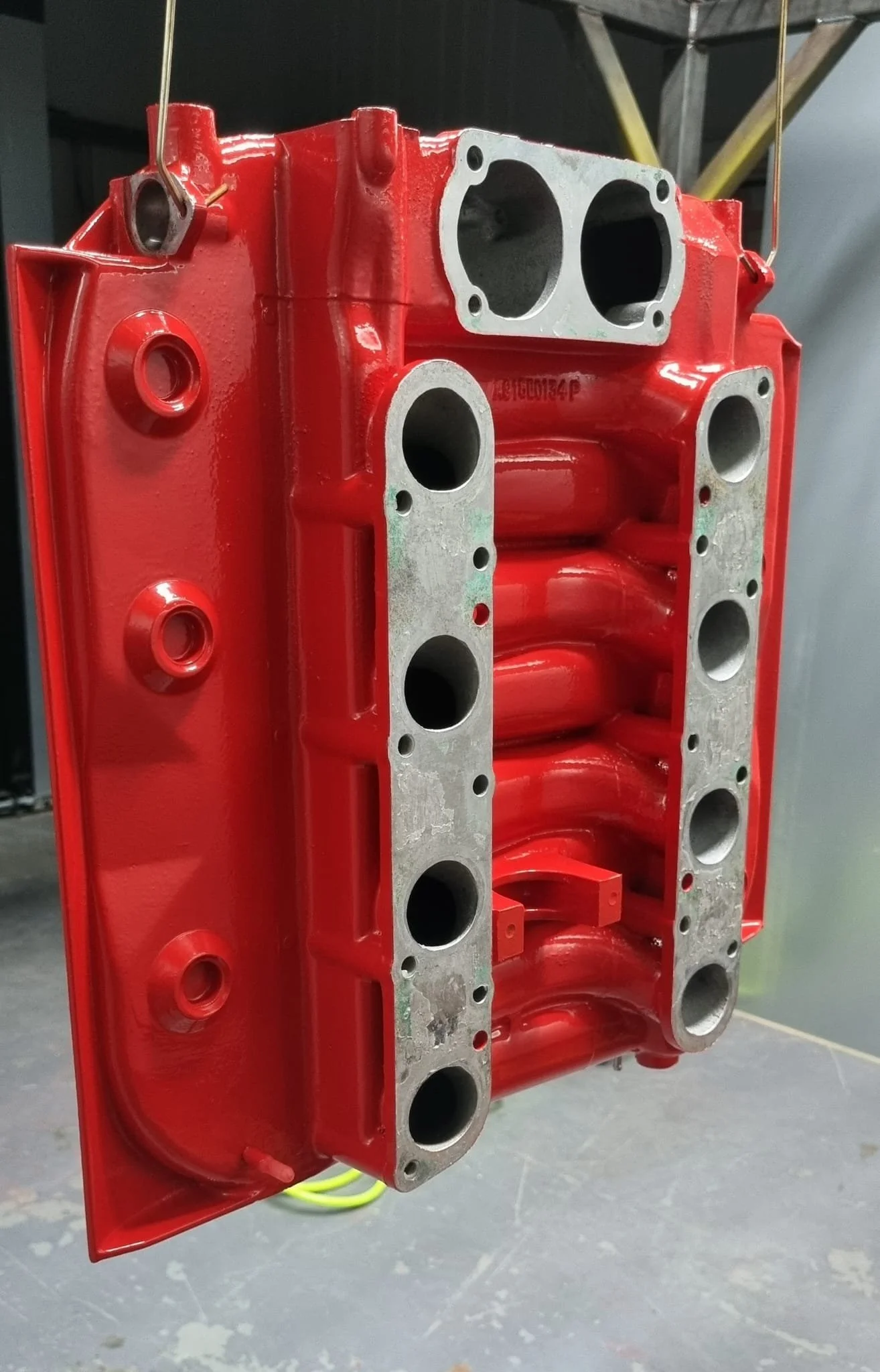 A red painted engine cylinder head with multiple intake and exhaust ports.