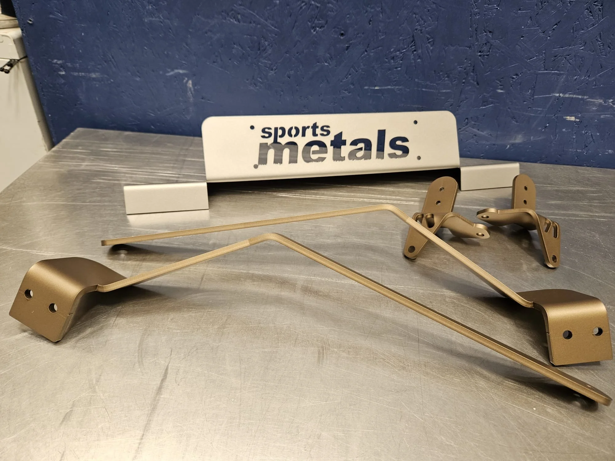 Metal stadium seats and a white sign with blue and gray text that reads 'sports metals' on a metal surface.