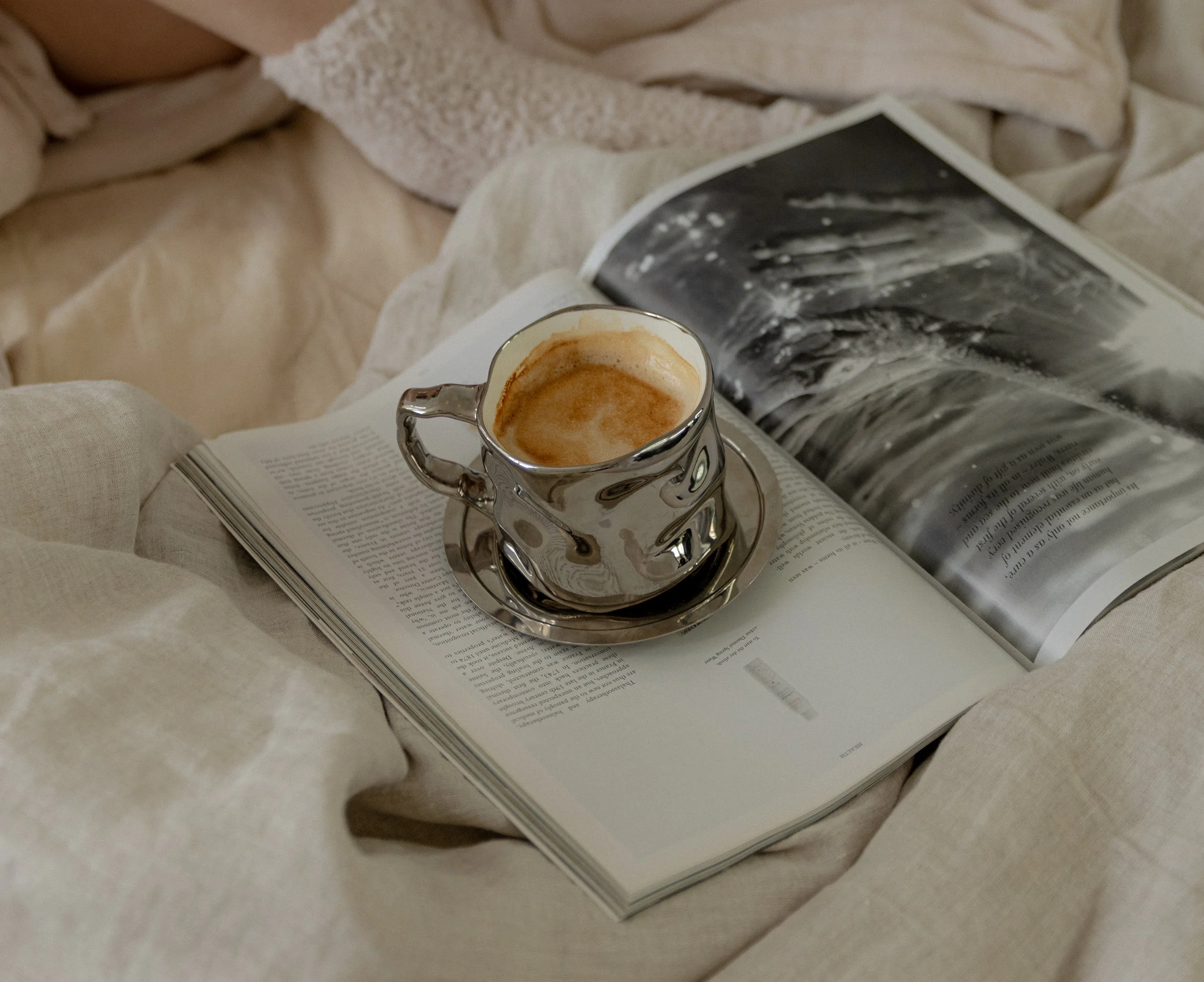 Magazine with silver cup of coffee on top of it.
