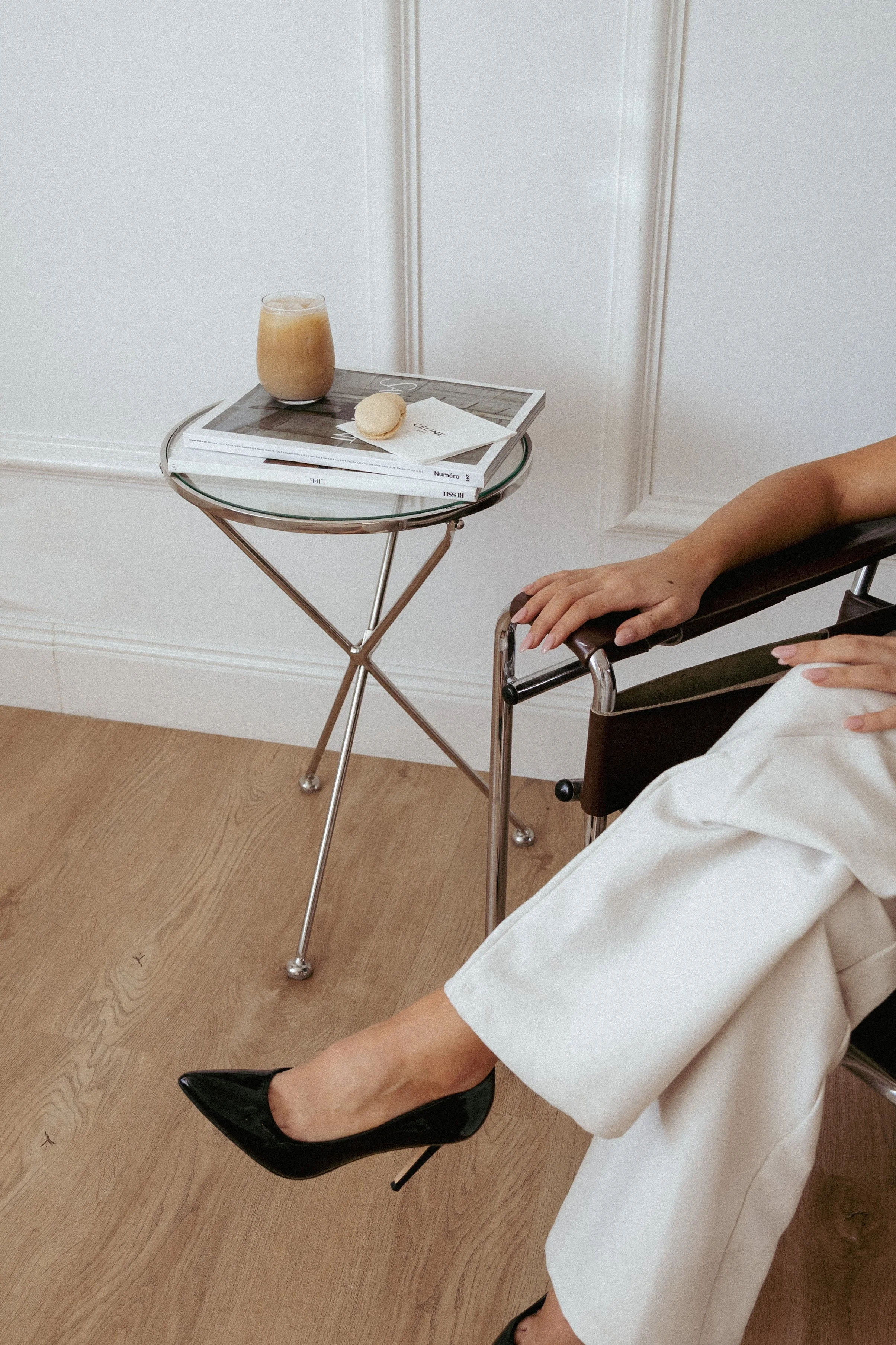 Woman sitting on a black chair near a table with a magazine and coffee.