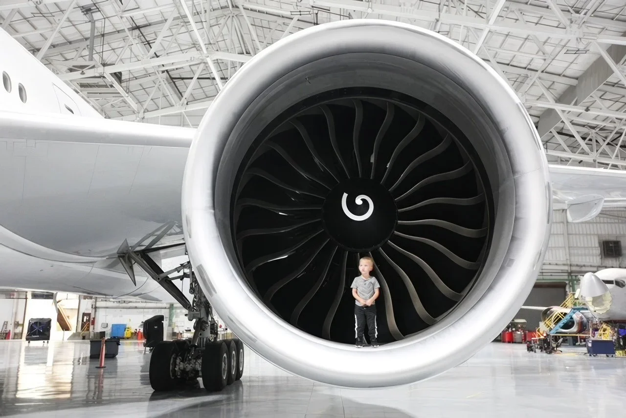 Young boy sitting on the wheel of a large airplane