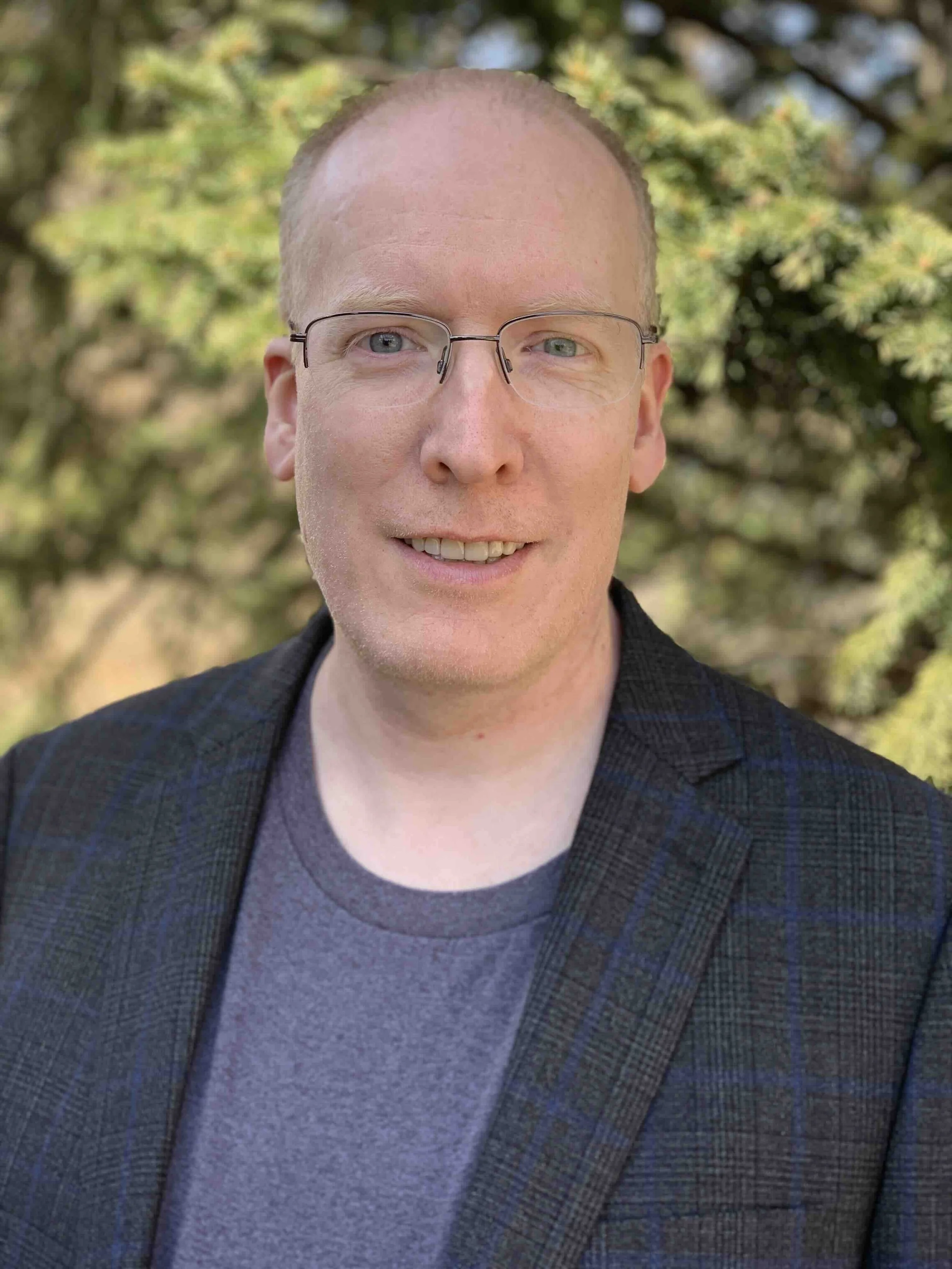 Professional headshot of Jeffrey outdoors in casual business attire