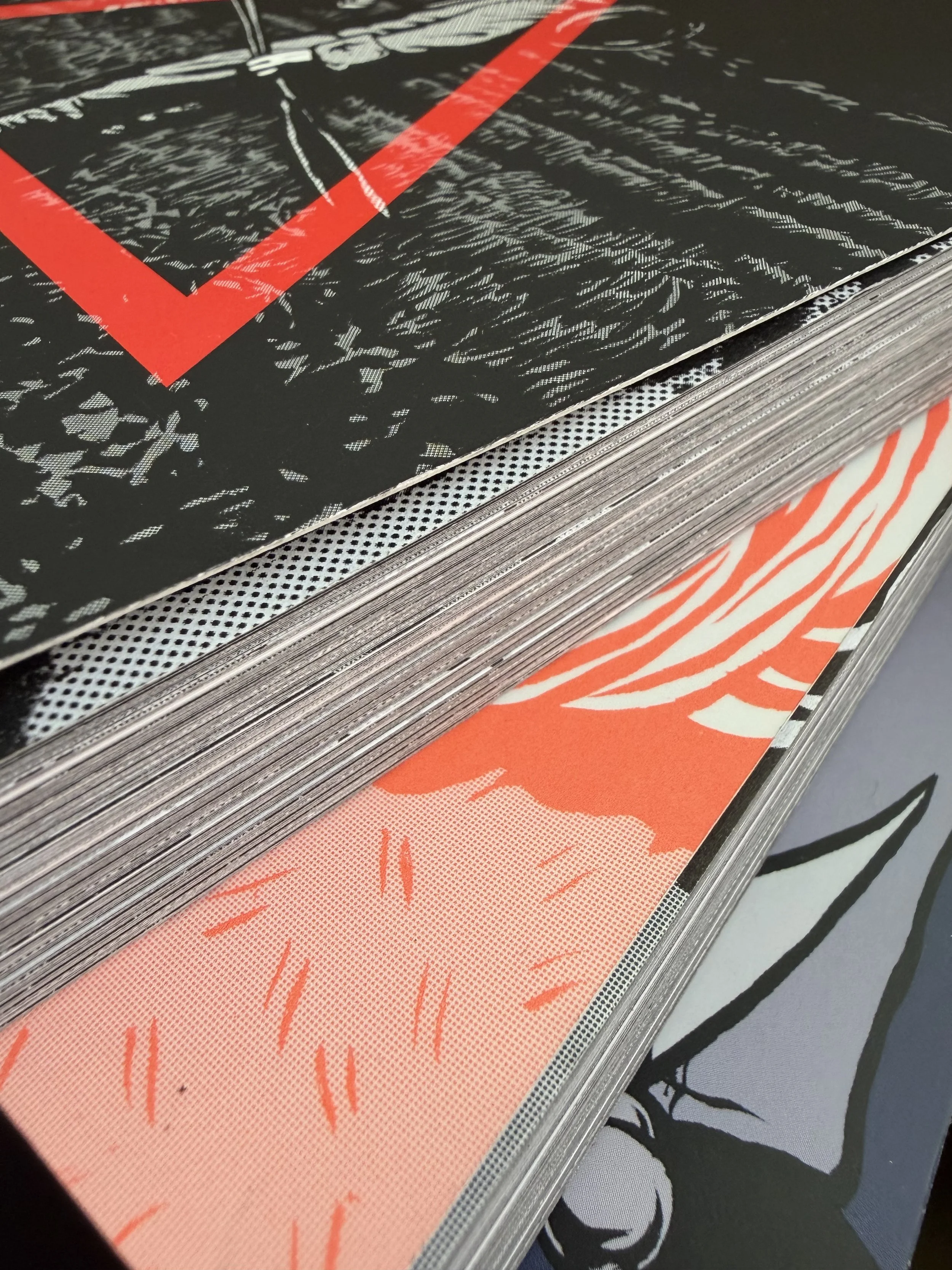 Close-up of a stack of comic books or graphic novels with colorful, illustrated covers, featuring bold lines and patterns.