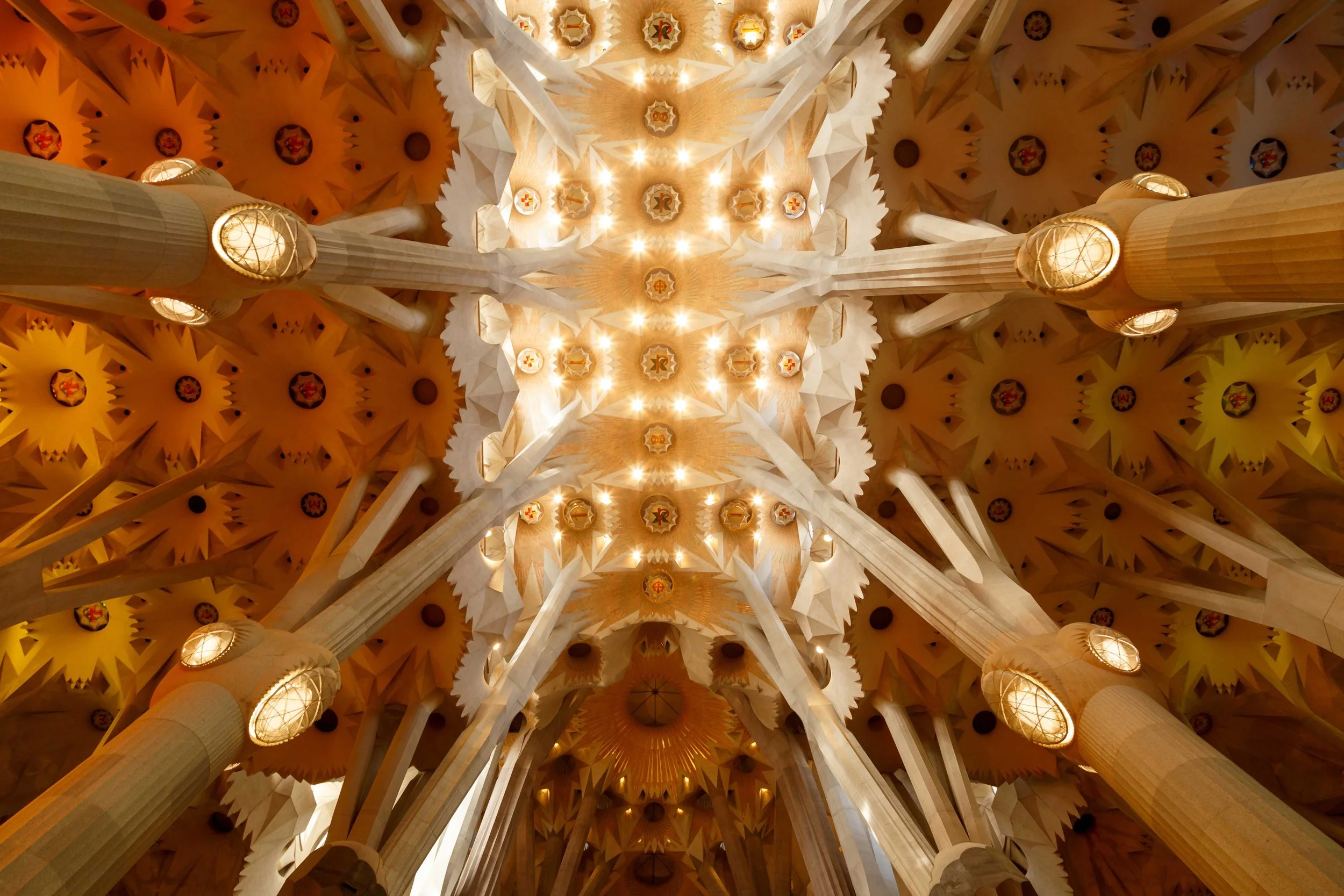 Vista del techo de la iglesia de la Sagrada Familia en Barcelona, mostrando las columnas, las formas geométricas y las luces que iluminan el interior.