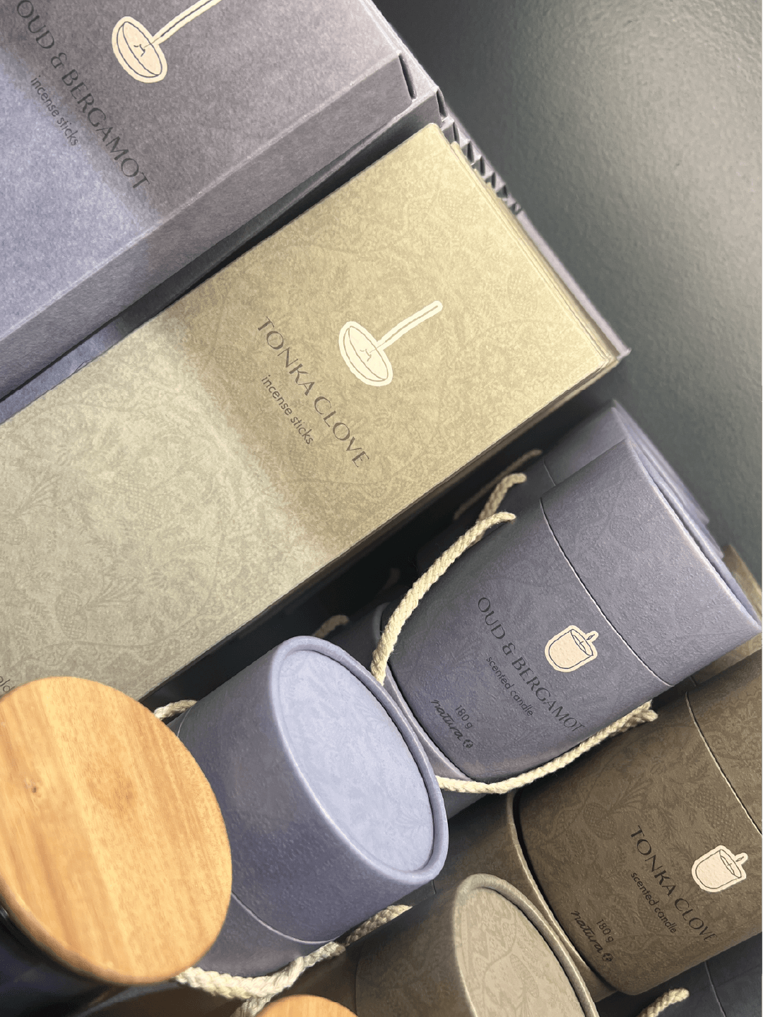 Boxes of incense sticks and scented candles from OUDA BERGAMOT, with packaging featuring minimalist illustrations and natural colors.