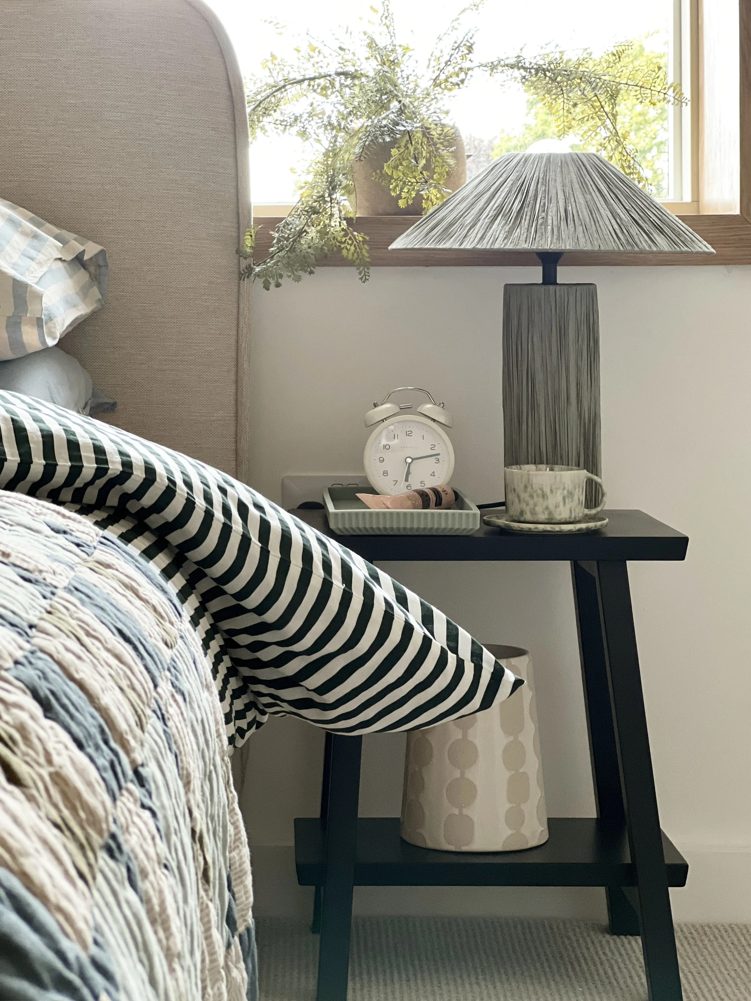 Close up of a wooden bedside table with a duvet cover pulled back invitingly