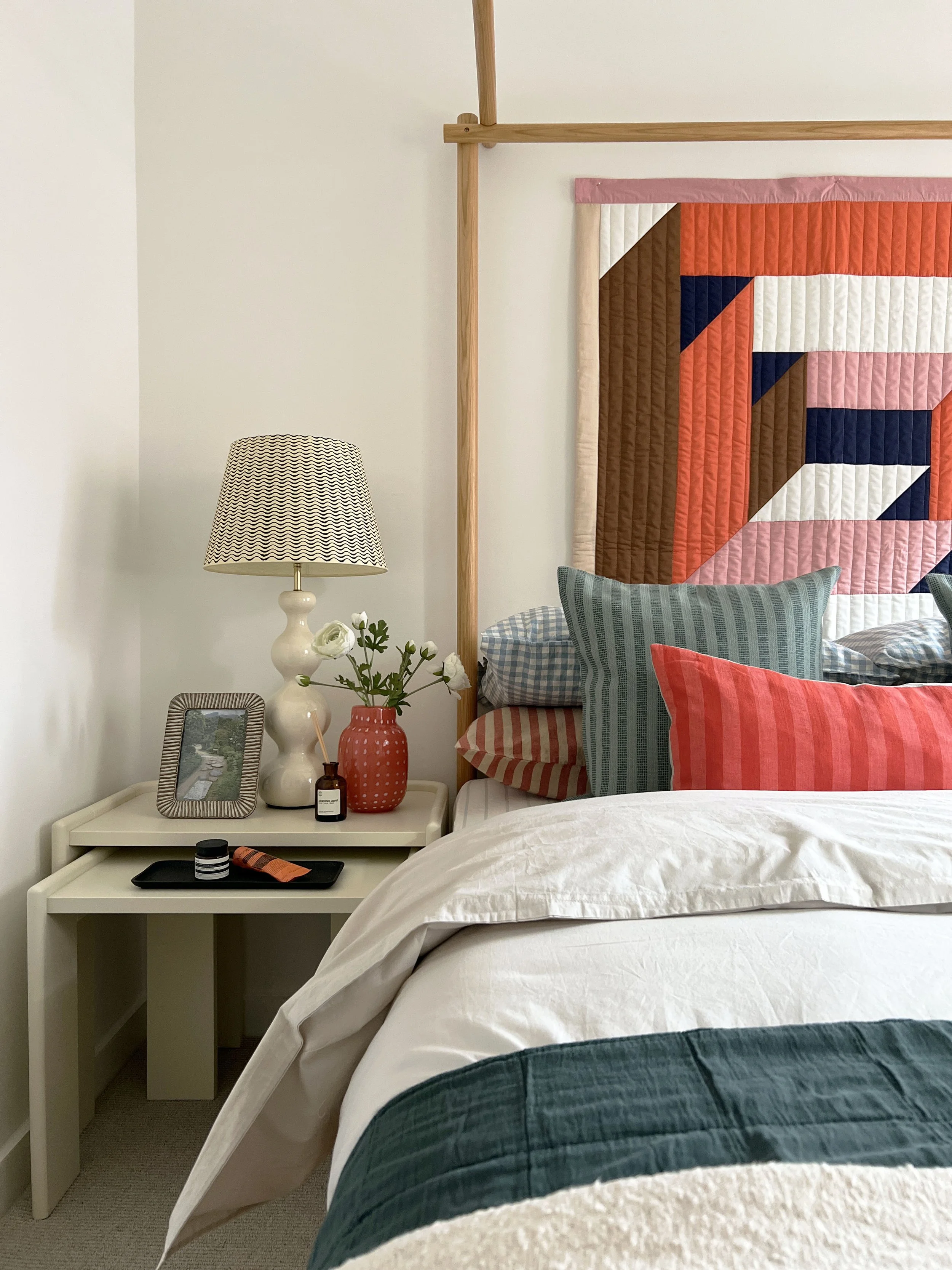 Side view of a fully dressed bed with unique fabric wall hanging to create movement and interest in the photograph