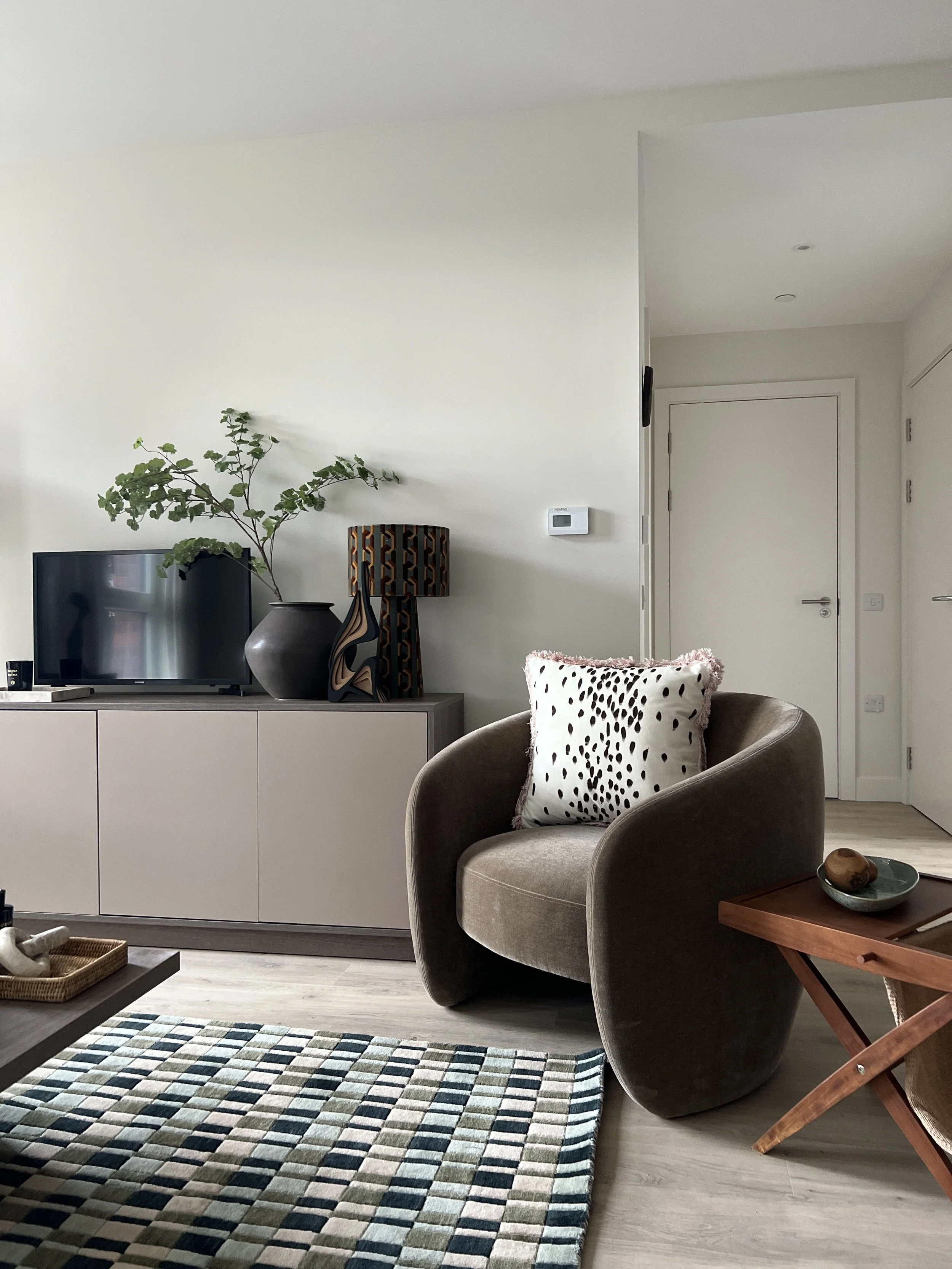 A curvy chair in a Fable designed show home.  A large patterned rug is showcased in the room