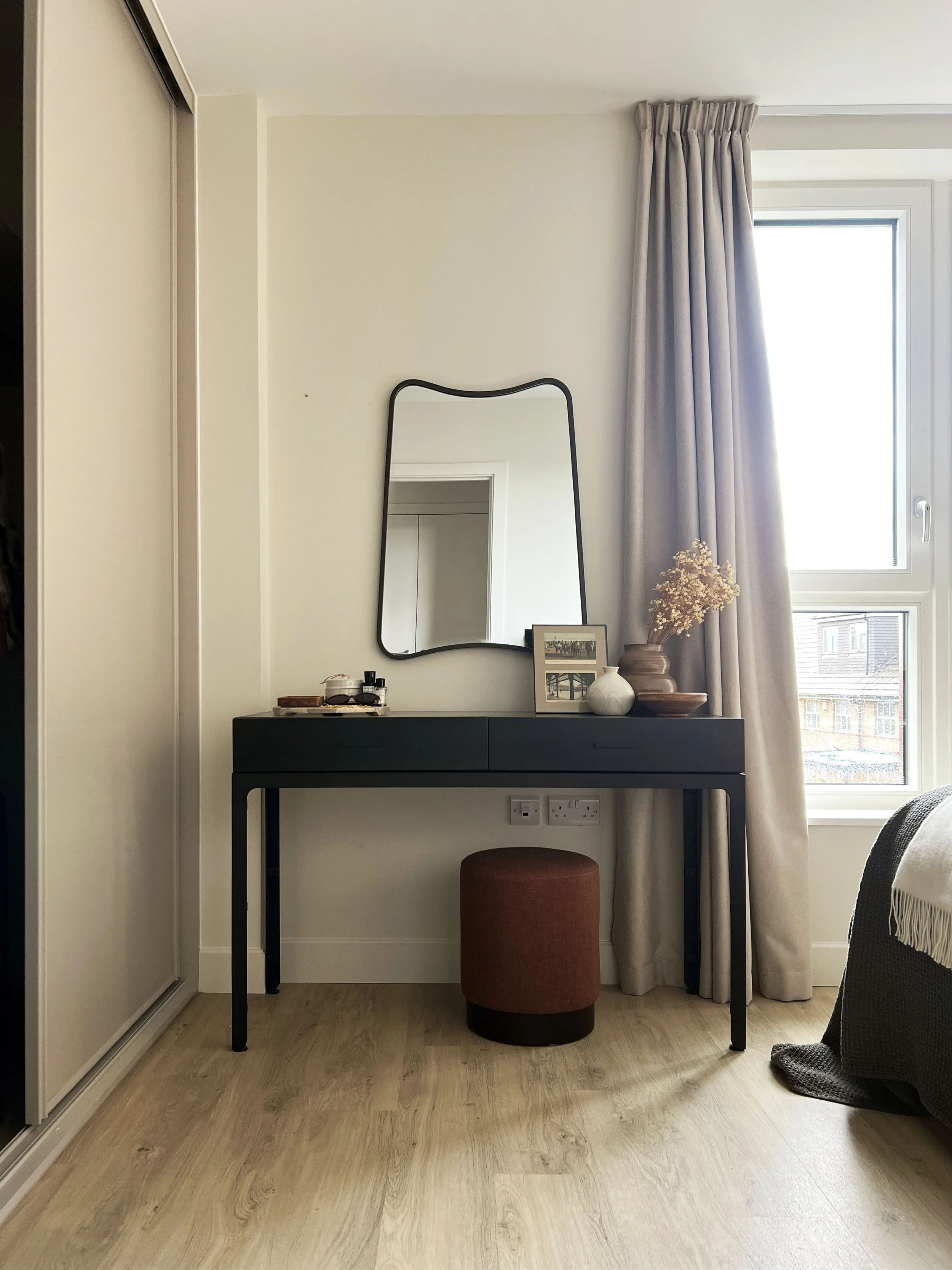 A serene make up space dressing table in dark wood with a large grooved mirror 