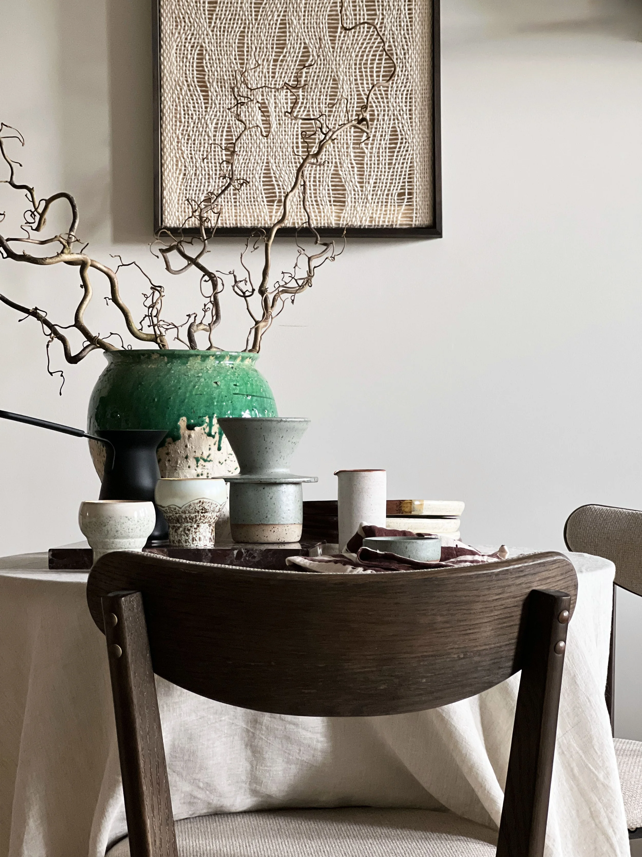 A dining table fully set, with a close up of a dark wood dining chair.