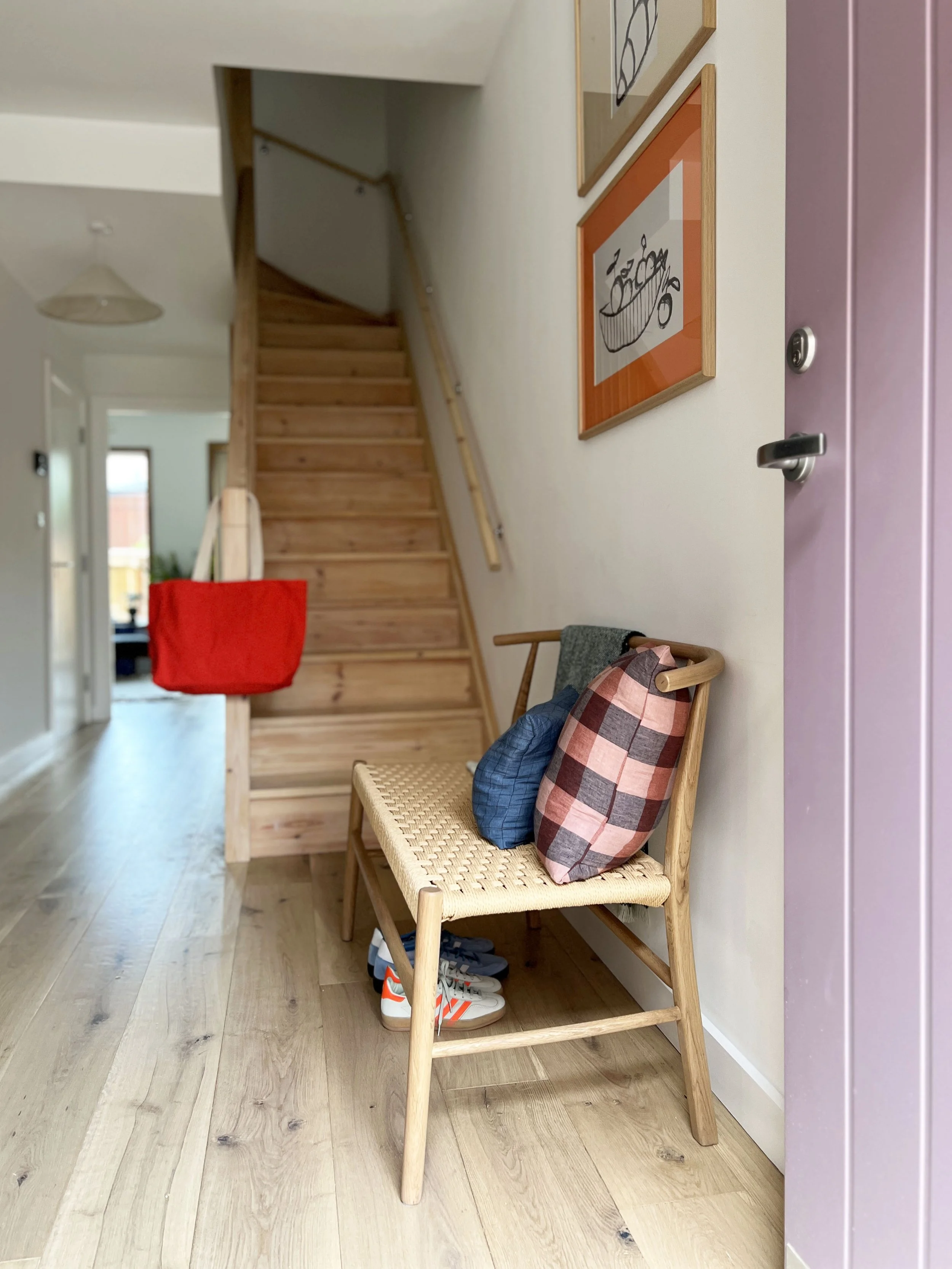 An open and airy show house entrance way with a beautiful wooden chair topped with a patterned pink and brown cushion