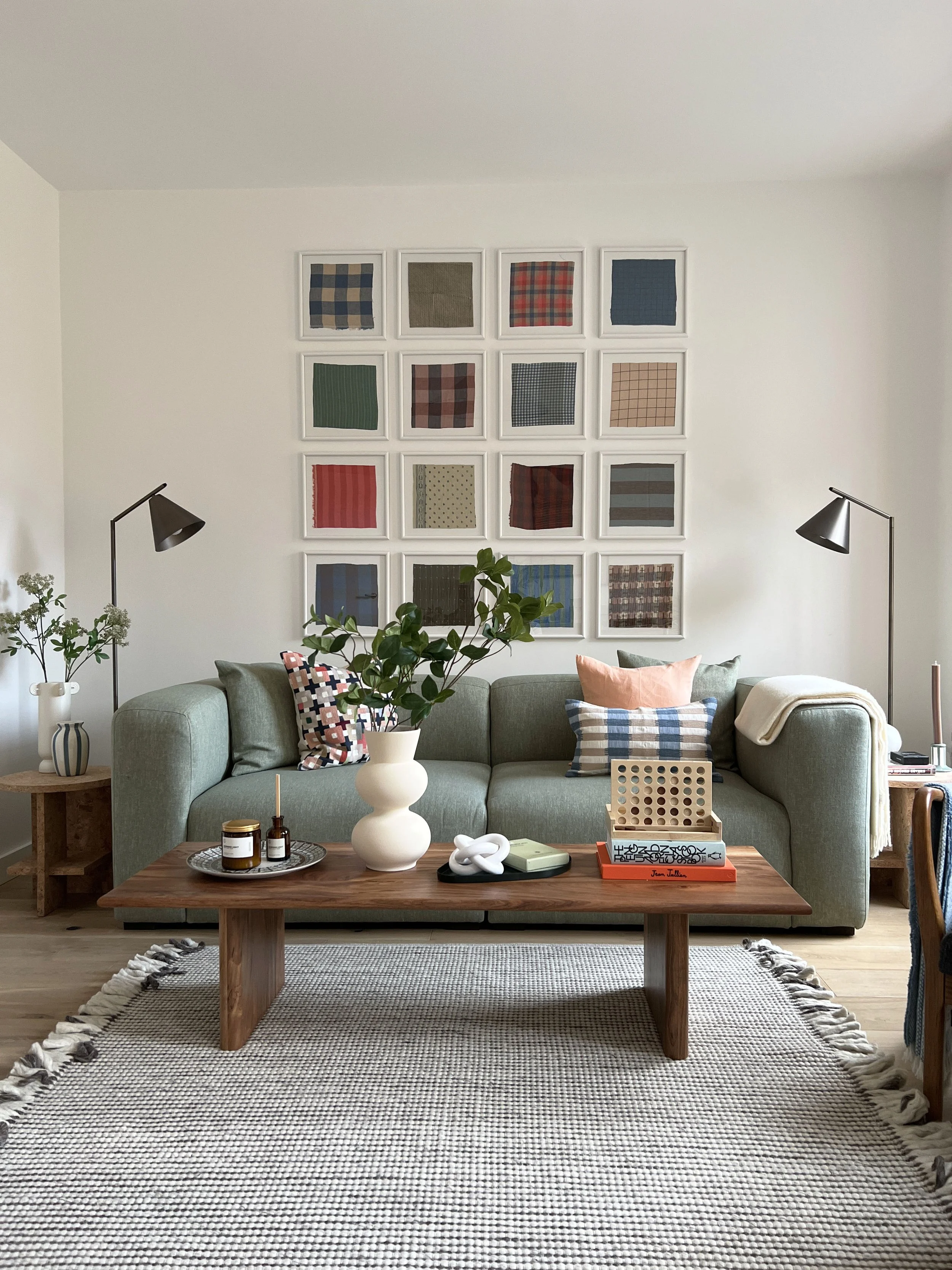 A large fabric gallery wall behind a neautral sofa in a bright and airy show house