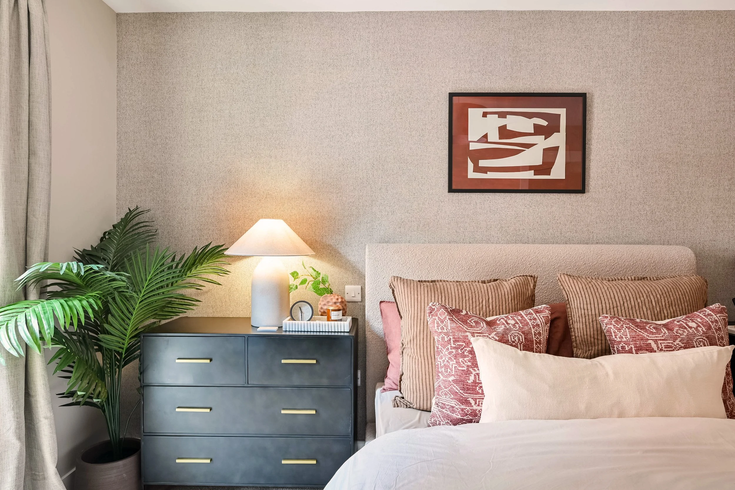 A calm and inviting bedroom with large green plant in a show home bedroom 