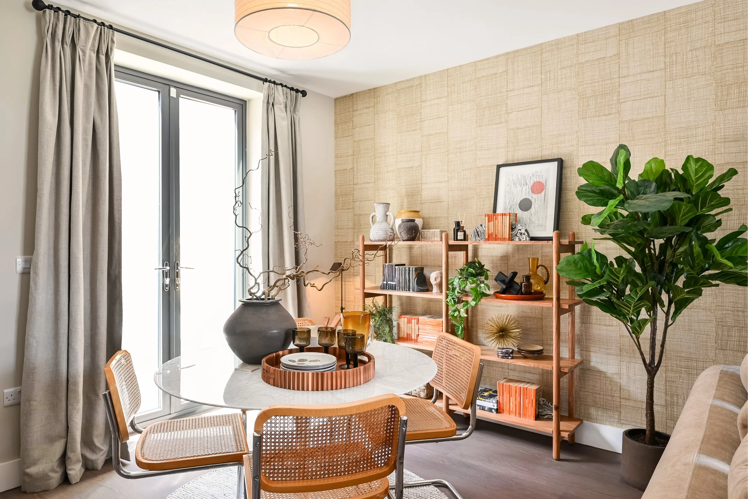 A round dining table accessorised with a large vase and shelving unit