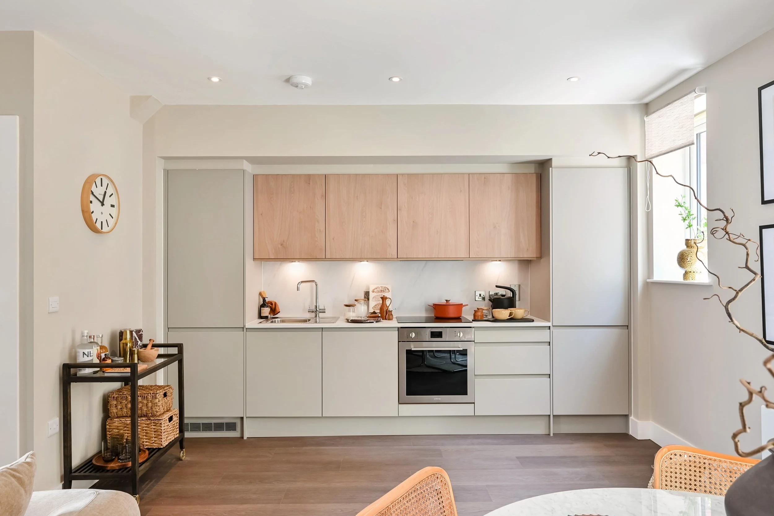 A simply designed white kitchen with units against a wall and styled for a show home setting