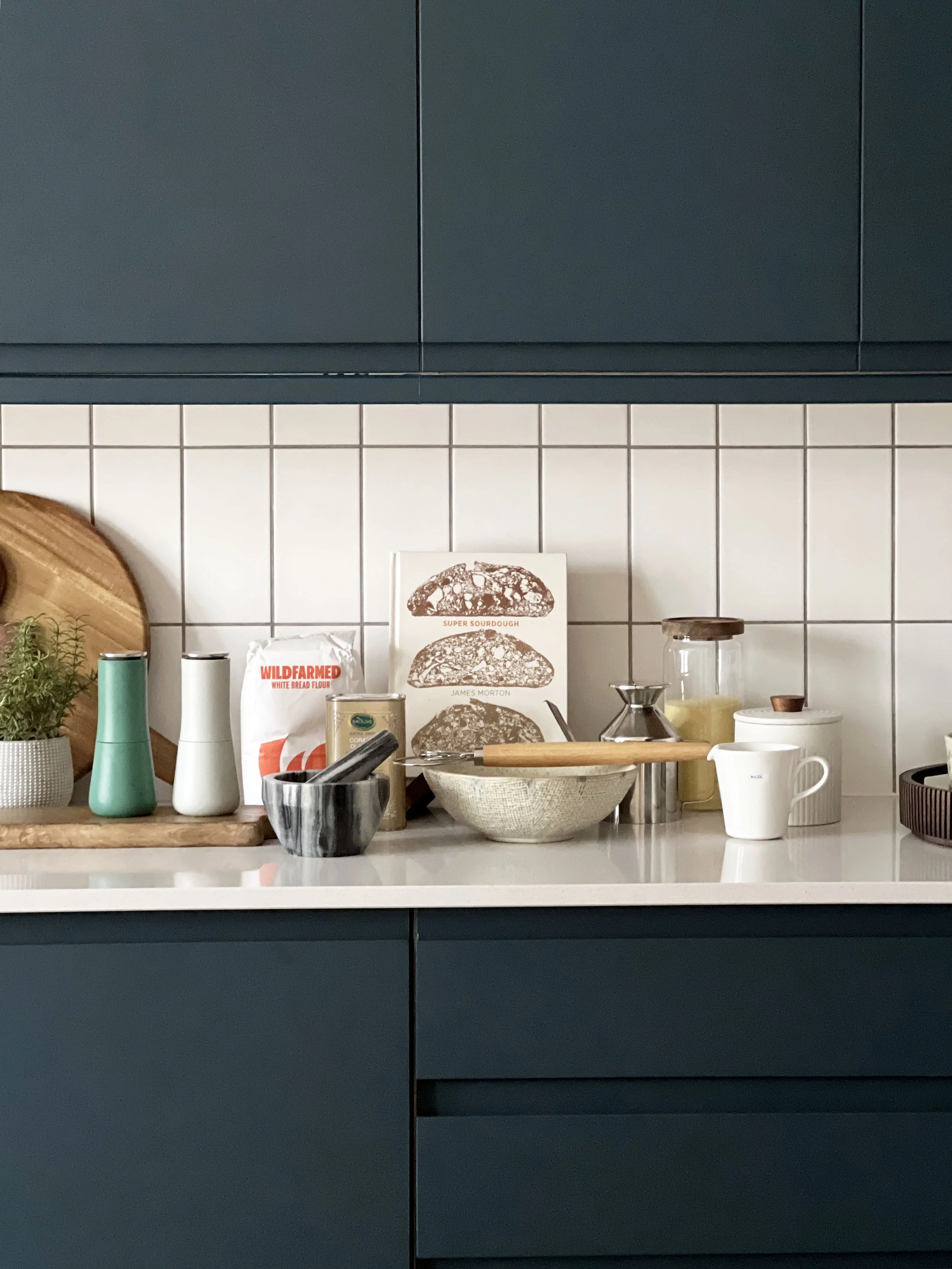 A dark kitchen with contrasting light worktops.  Accessorised for a show home style viewing with small kitchen items