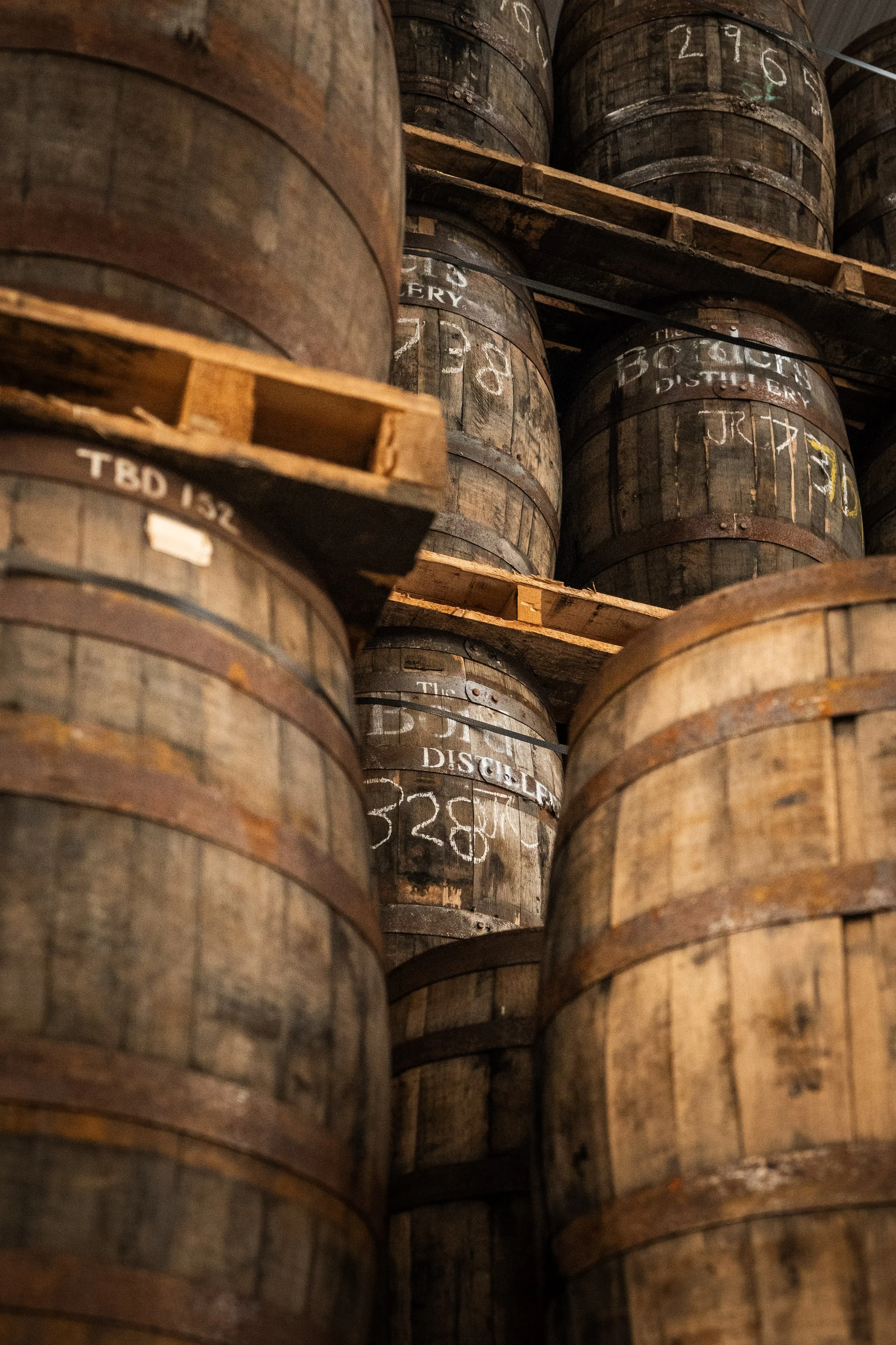 Close-up view of stacked wooden barrels in a distillery warehouse.