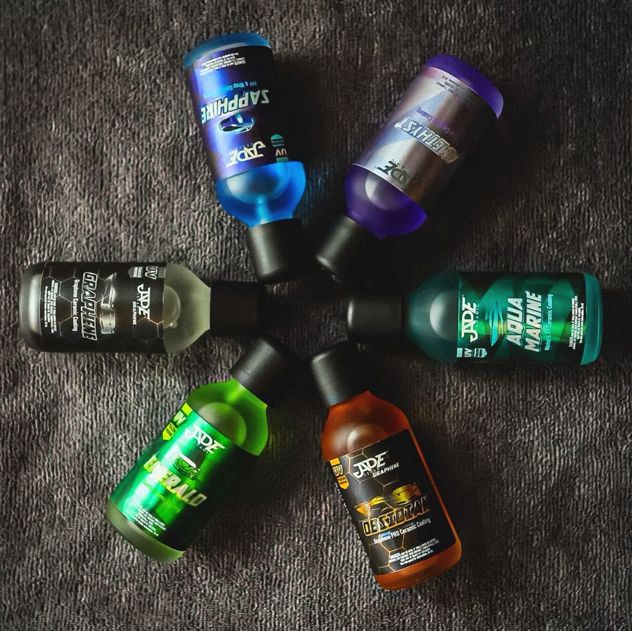 Six bottles of Jade brand ceramic coatings arranged in a star pattern on a black textured surface.
