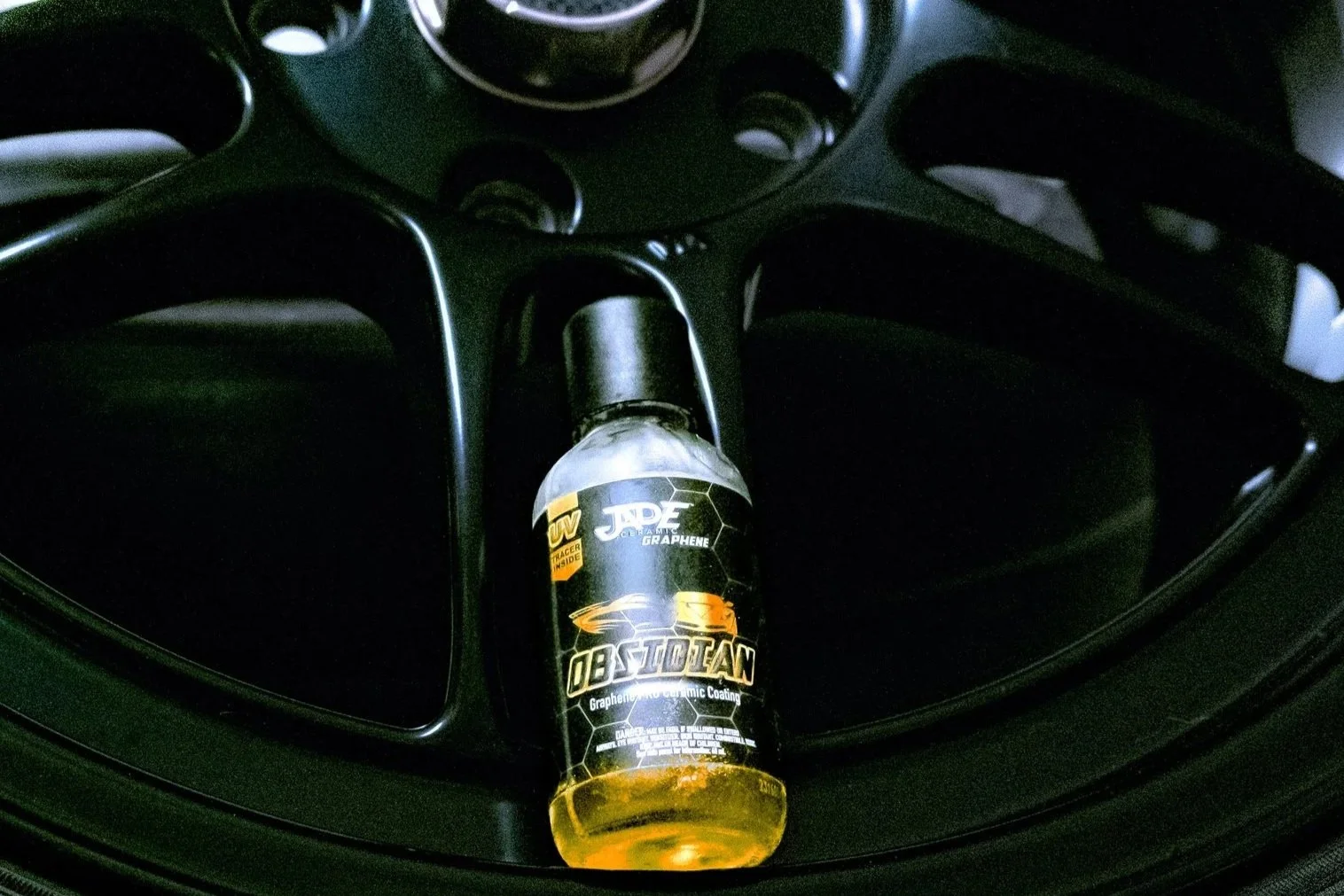 Bottle of Jade Obsidian 7-year ceramic coating sitting on a black wheel