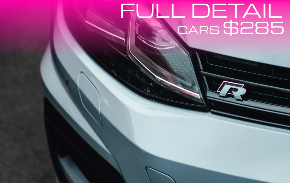 Close-up of the front of a white car with an 'R' badge, black grille, and headlight, with pink text overlay advertising full detail service for $285.