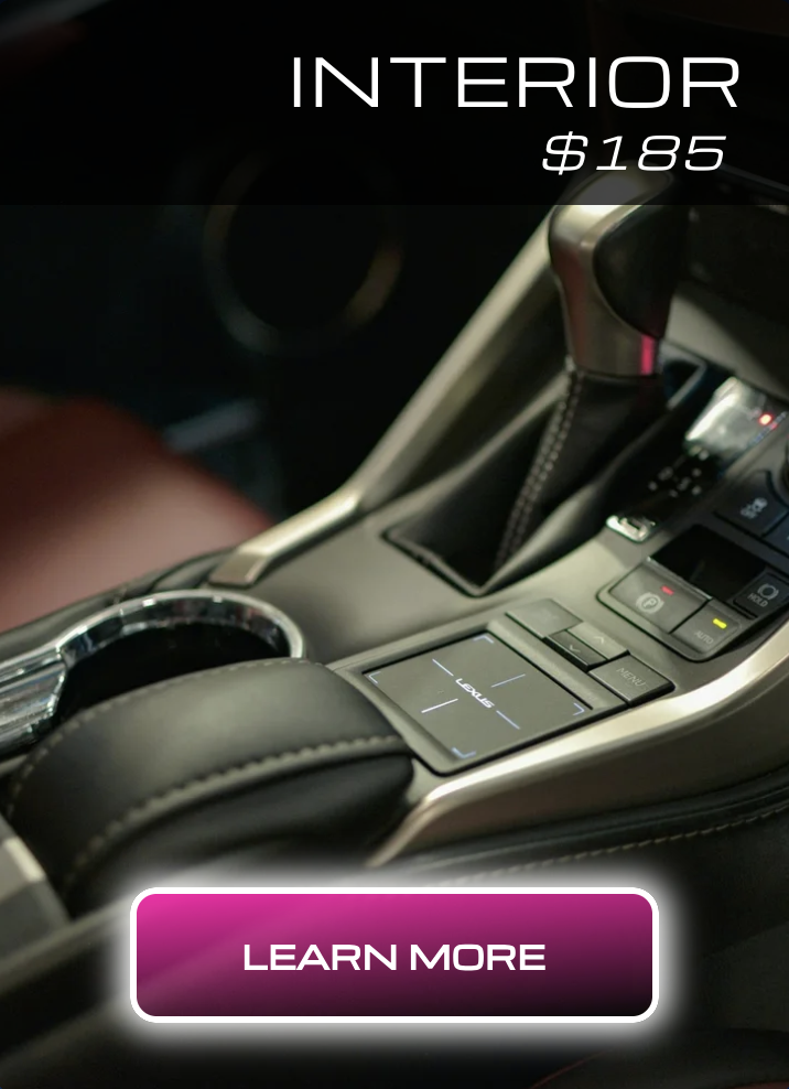 Close-up of a car interior, focusing on the center console with gear shift, control buttons, and touchpad.