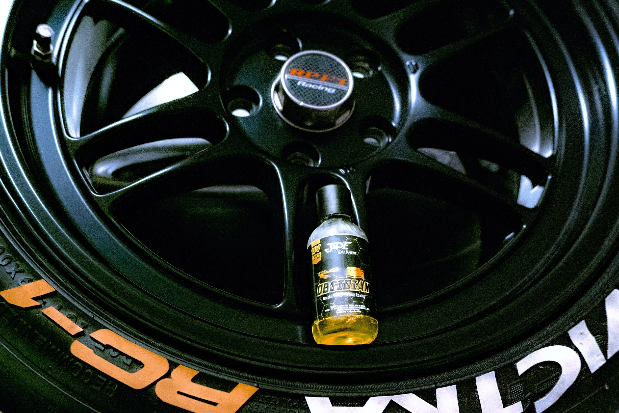 Picture of a ceramic coating bottle on a car's wheel.