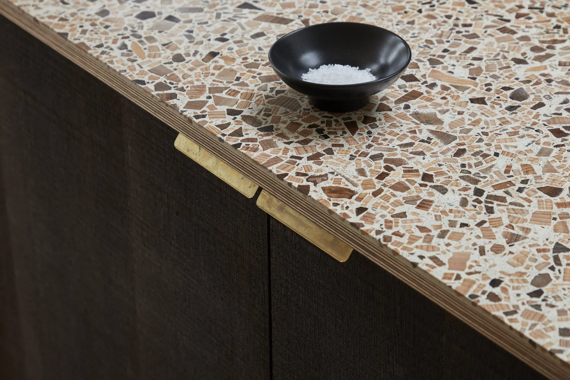 Close-up of a bathroom or kitchen countertop with a black bowl containing salt.
