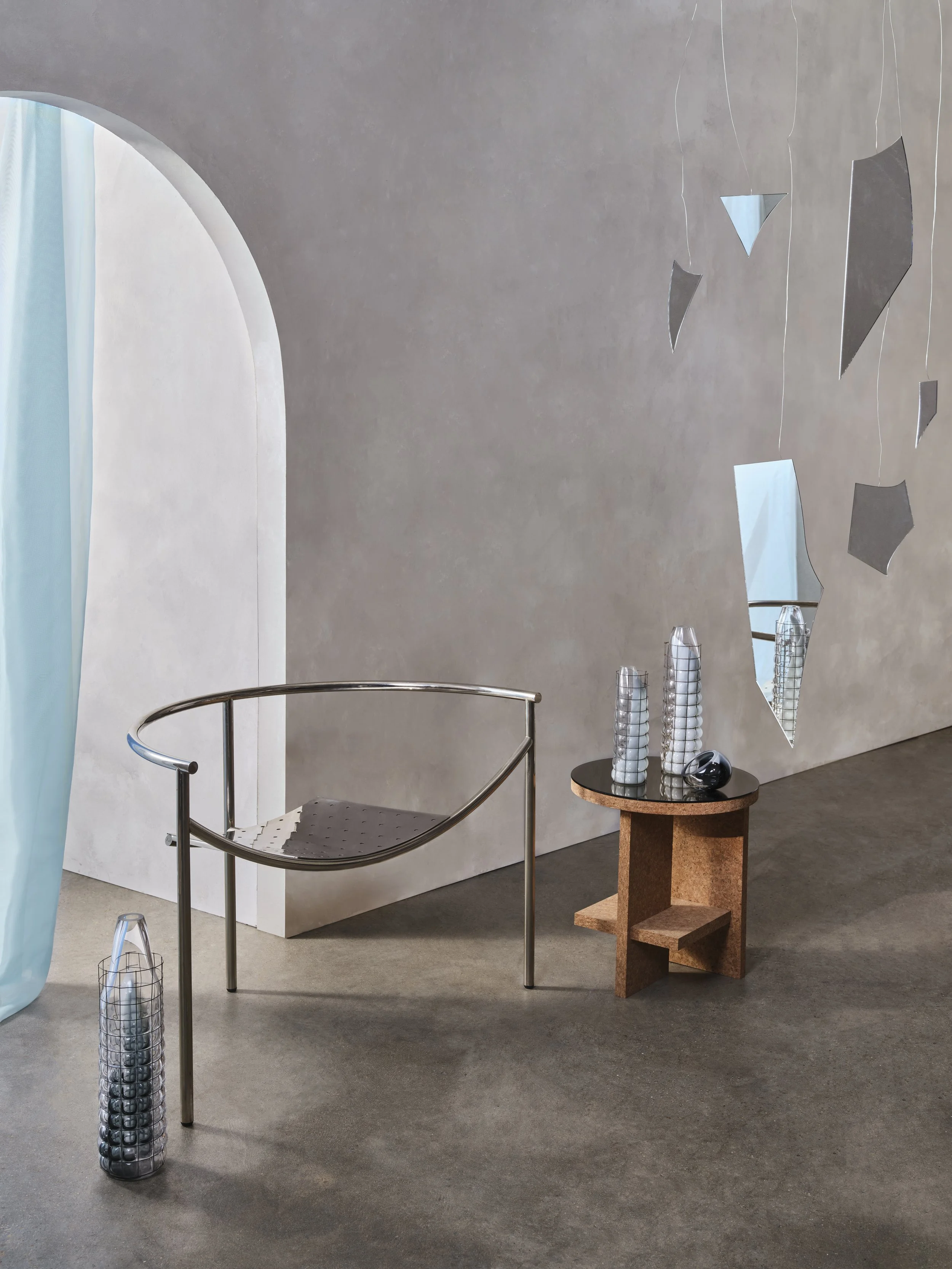 Minimalist interior with a modern metal bench, a wooden side table with vases, and a wall mirror with geometric shapes.