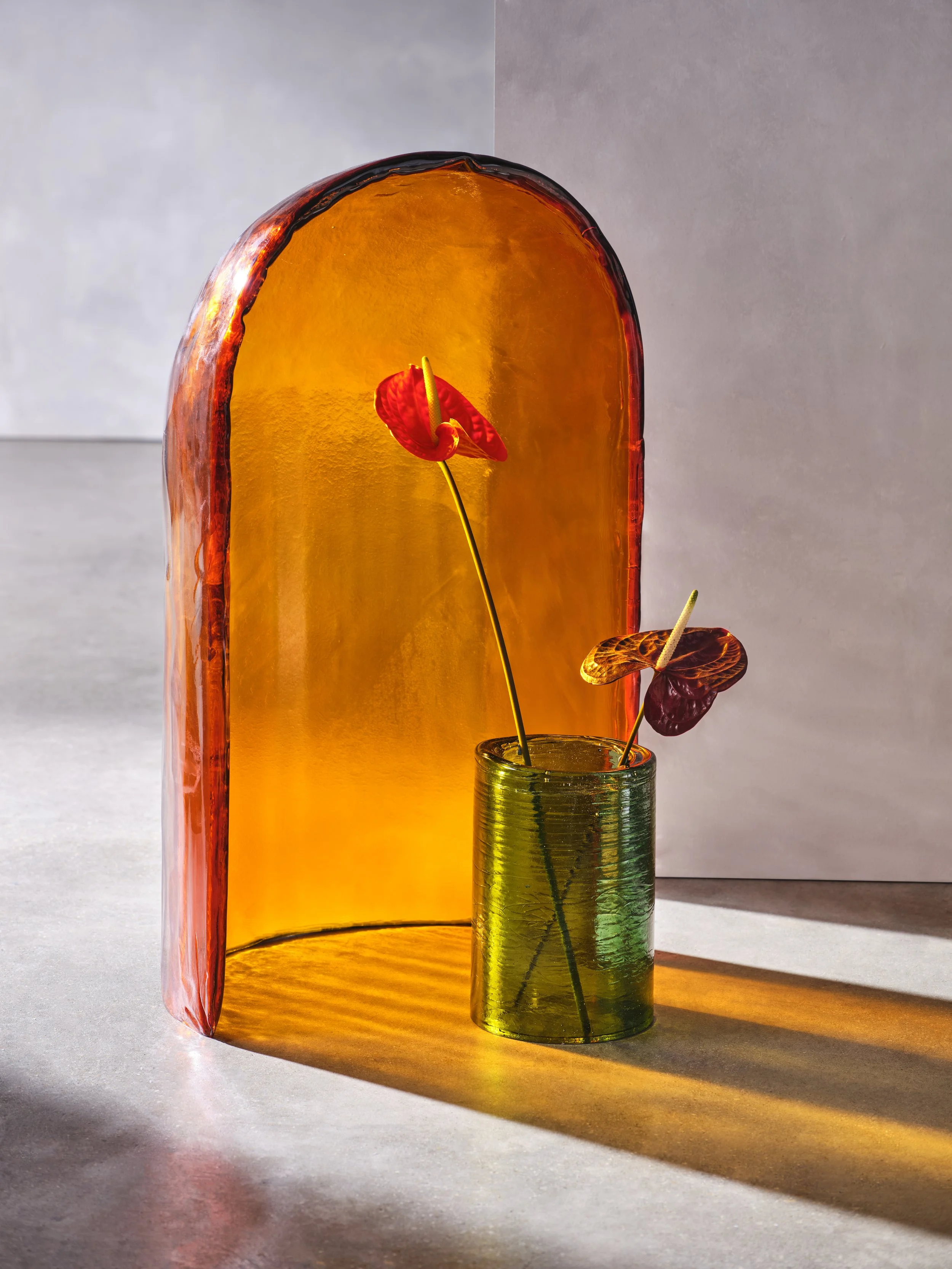 Decorative glass objects with colorful flower-like accents on sticks, showcasing light and shadow effects.