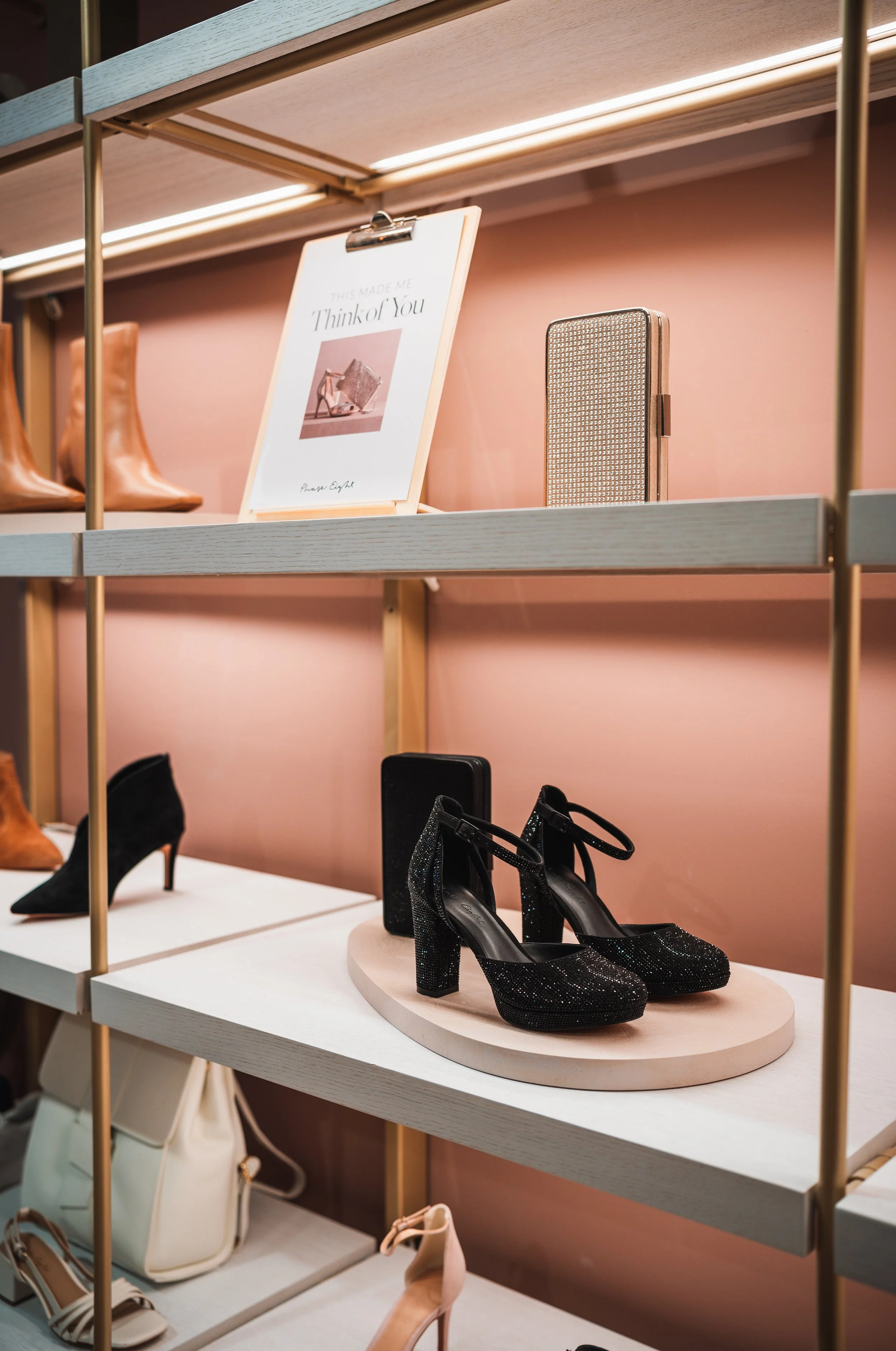 Black high-heeled shoes with ankle straps on display in a retail store.
