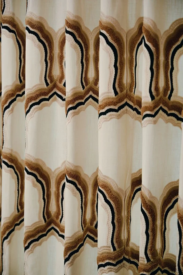 Patterned curtain with wavy, layered designs in beige, black, and brown colors.