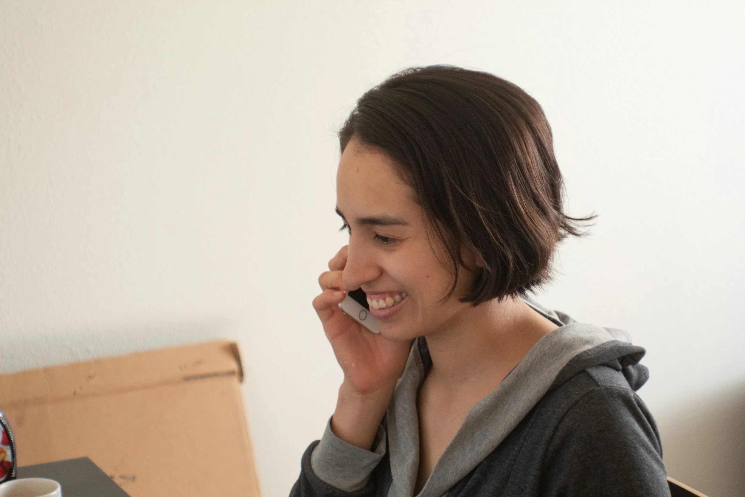 Woman with short brown hair smiling while talking on a smartphone.