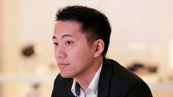 A man in a business suit sitting in an office setting.