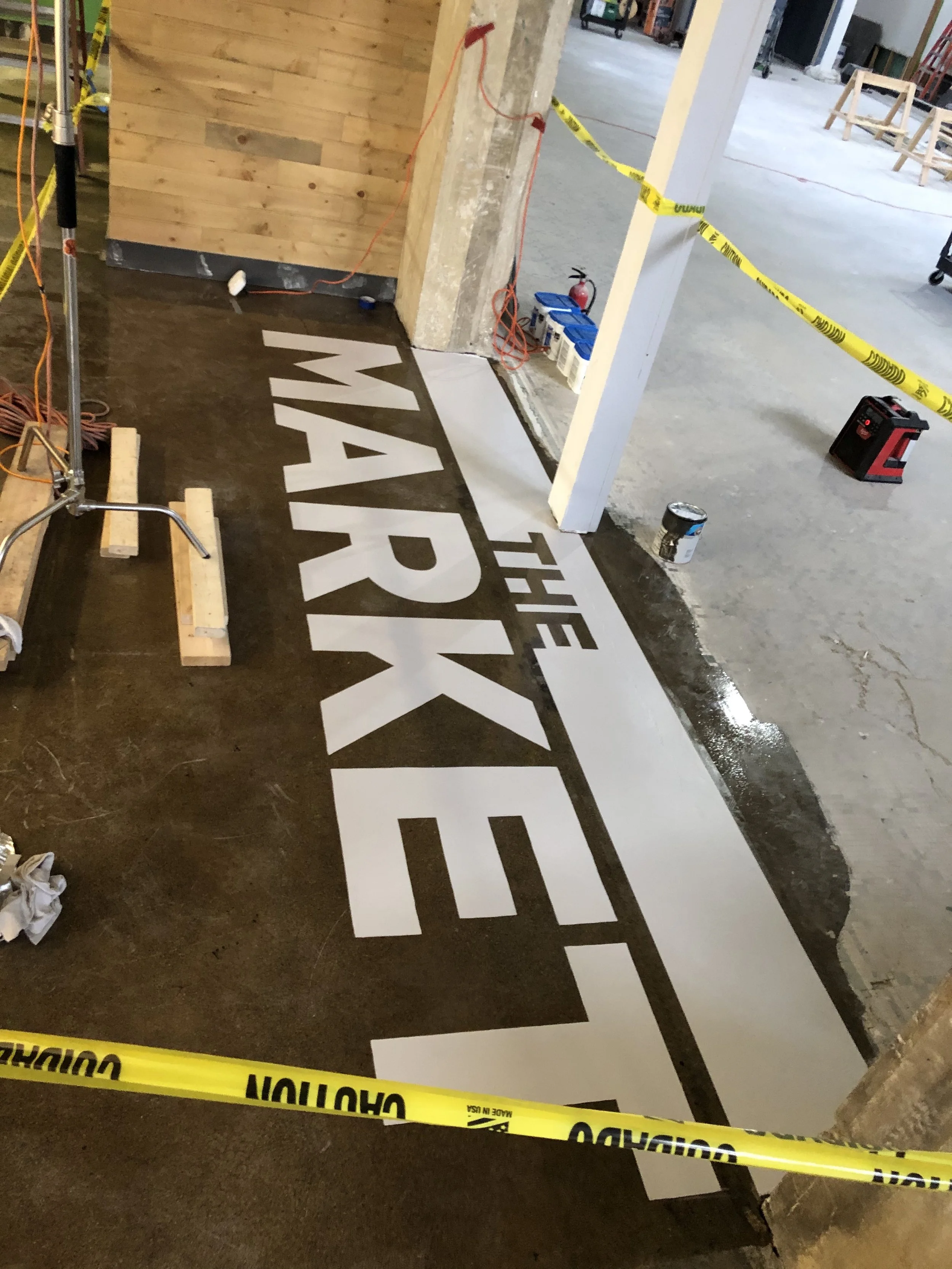 Hand painted wayfinding on metal pole and wall directing customers to "Order here" and the restrooms and elevator