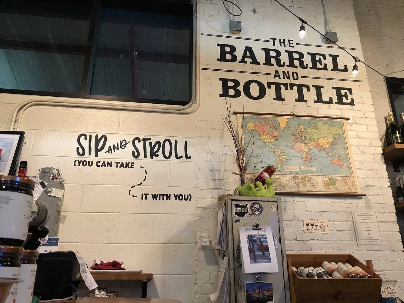 Hand painted Barrel and Bottle logo on brick; Hand painted hand lettering wayfinding on cinderblock encouraging guests to 'Sip and Stroll'.