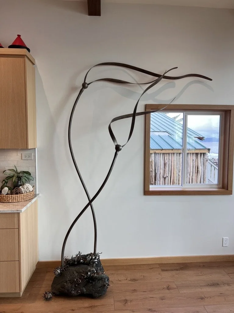 Finished sculpture based on concept sketch of bull kelp on stone base in a home
