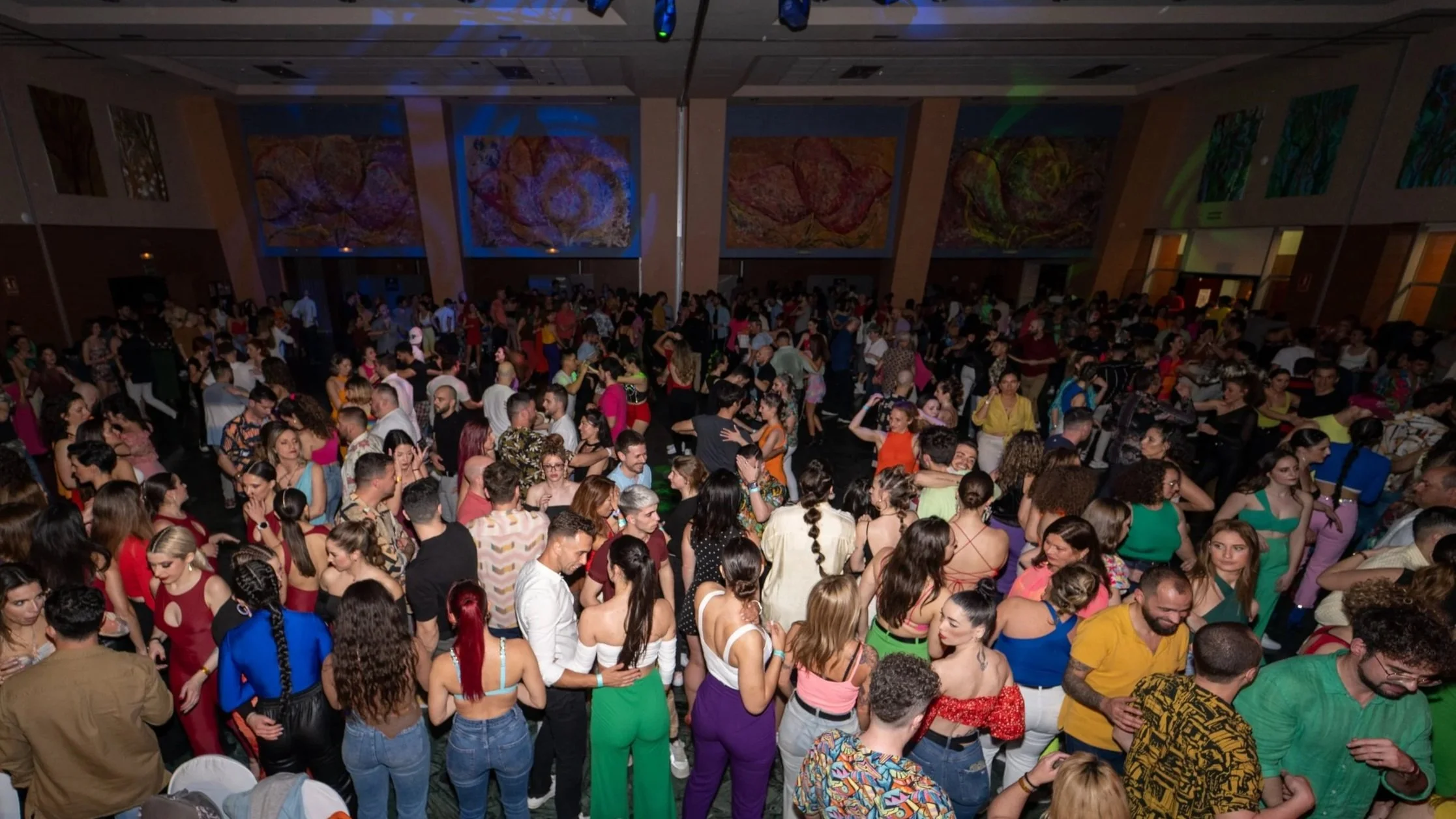 Imagen de una multitud de personas bailando en un evento social en un salón grande.