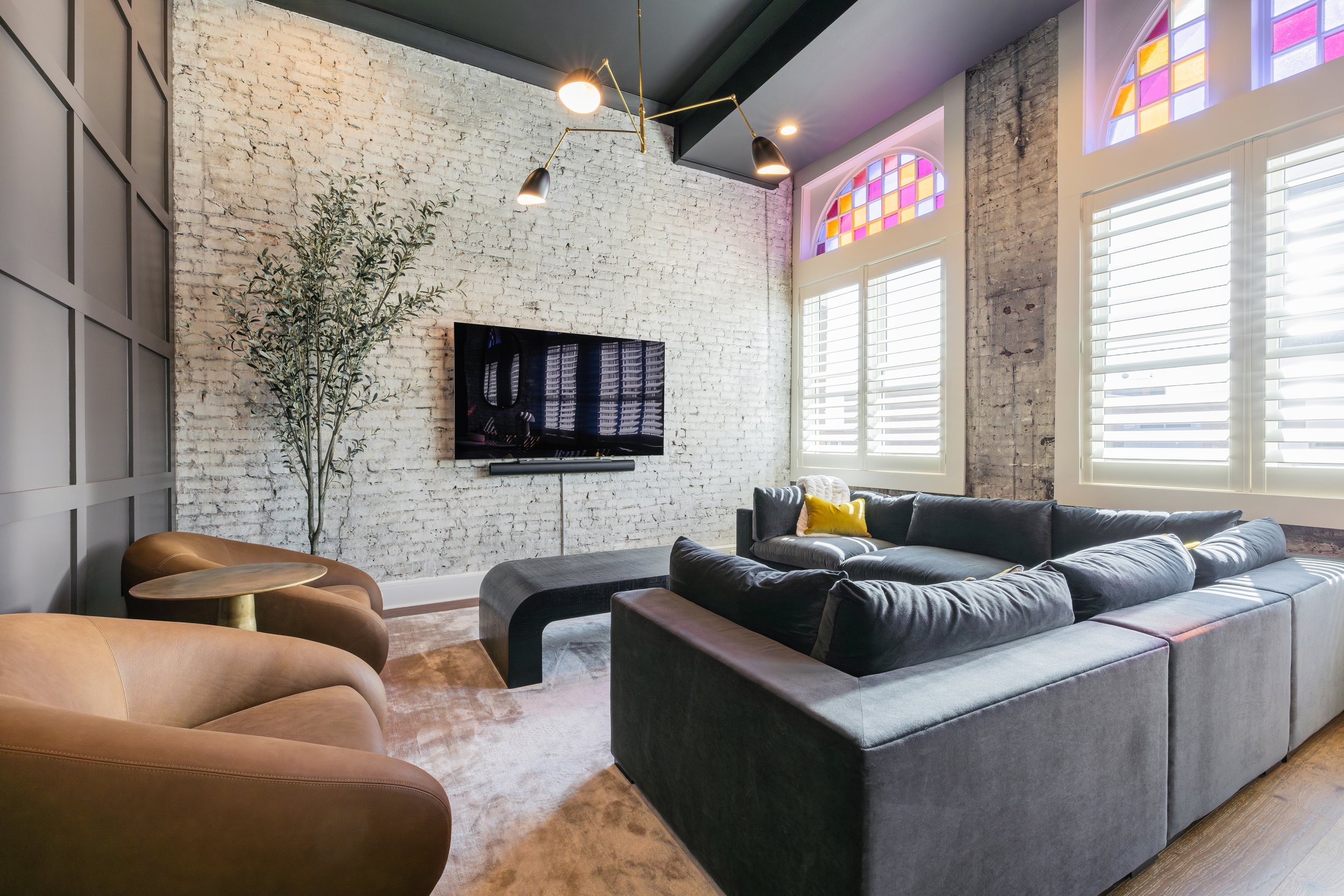 Lounge with a white brick wall, stained glass windows, and leather armchairs.