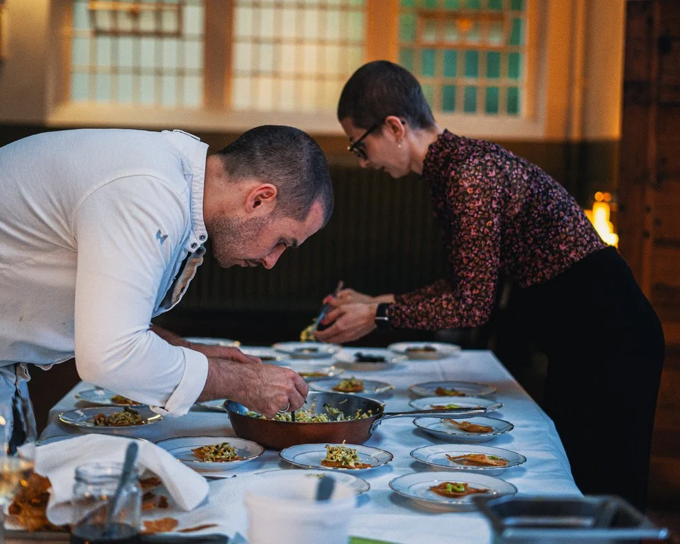 Two chefs garnishing dishes at a restaurant kitchen.