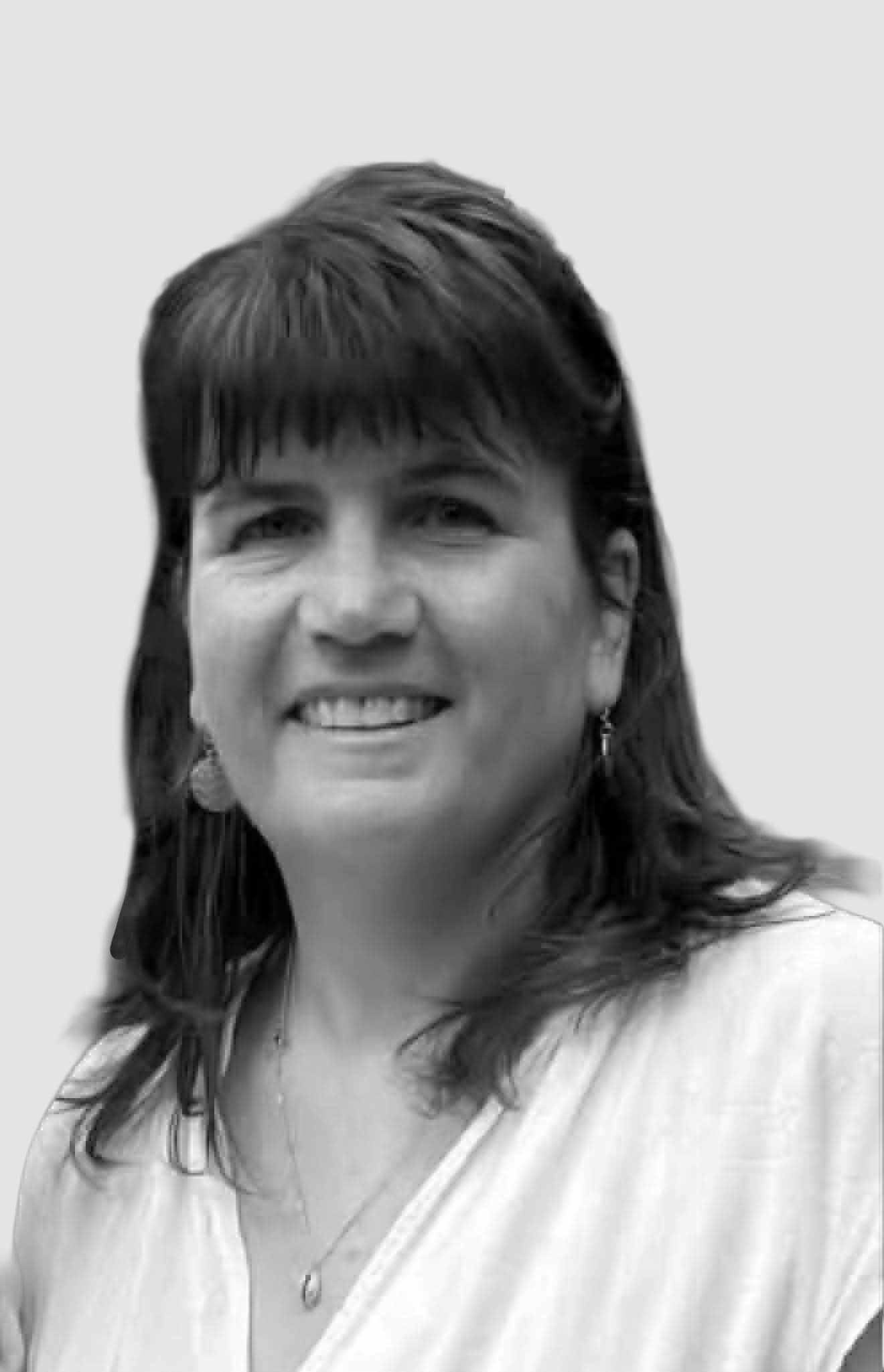 Black and white photo of a smiling woman with shoulder-length hair wearing a light-colored top.