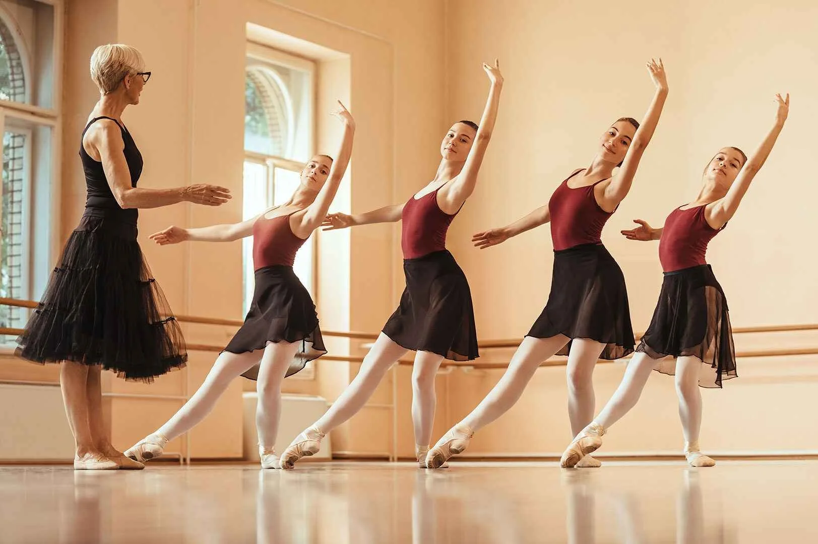 Ballet instructor with five young ballerinas practicing at the ballet studio.