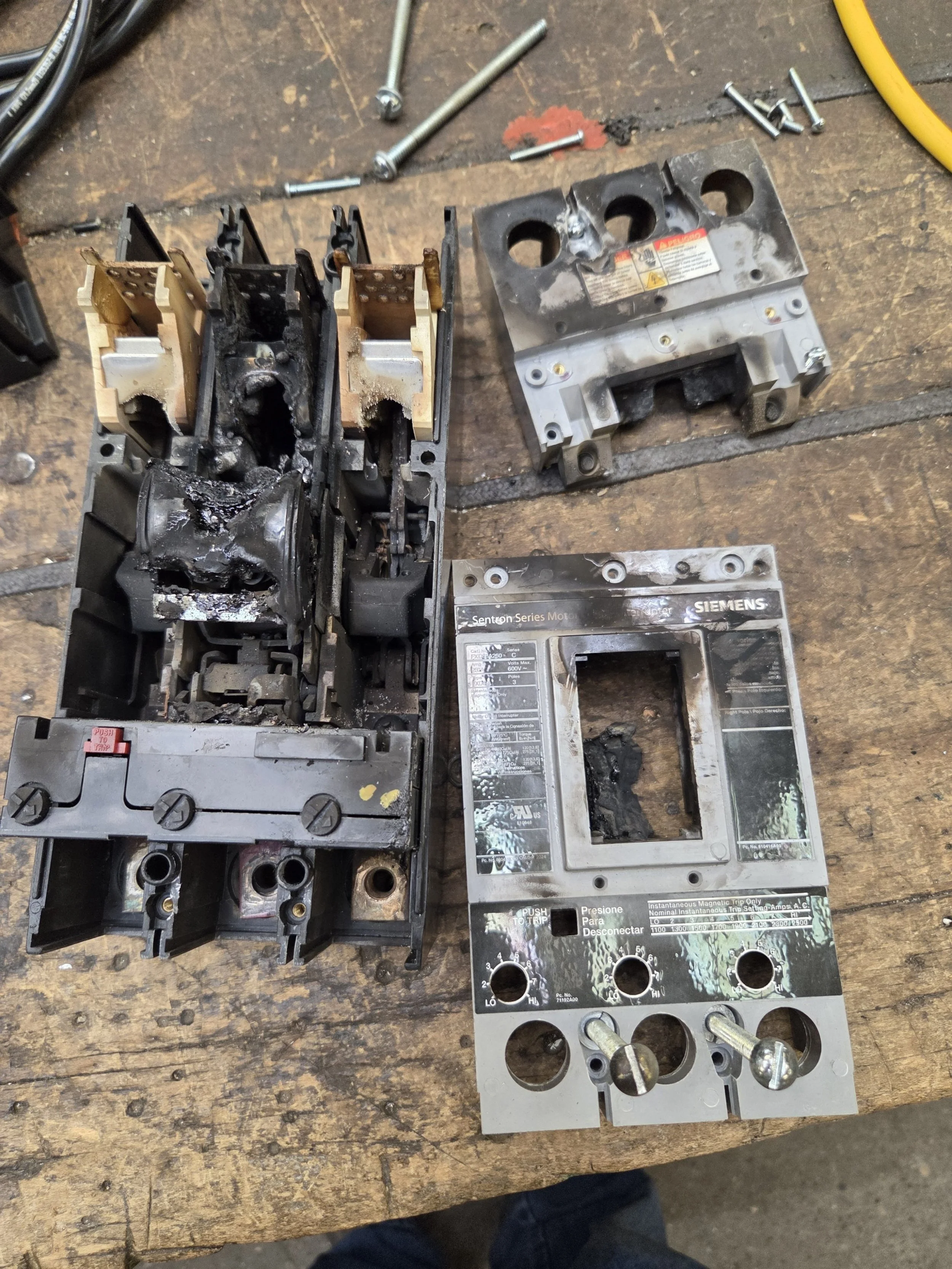 Burned and melted electrical circuit breaker components, with parts disassembled on a workbench. Thermograpics. Thermograpy.  Unseen electrical problems. Hot wire. Hot contacts. Resistance at termination. Loose terminations.