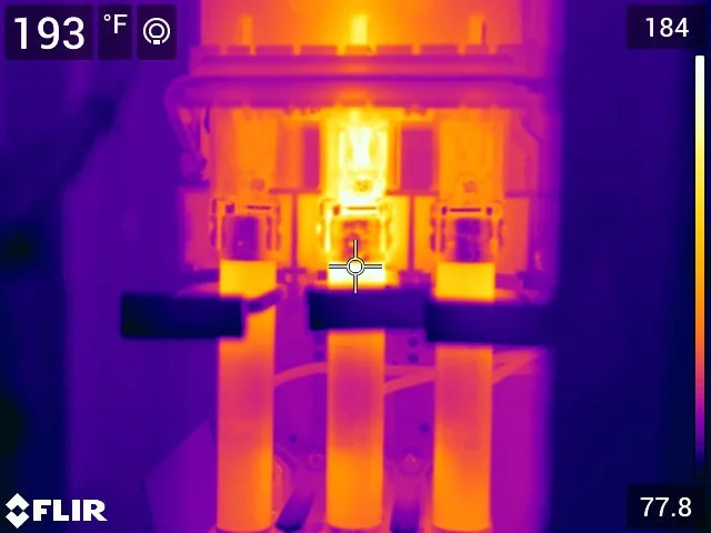 Thermal image of electrical equipment showing high heat levels, with temperature around 193°F, highlighting components in bright yellow and orange edges.