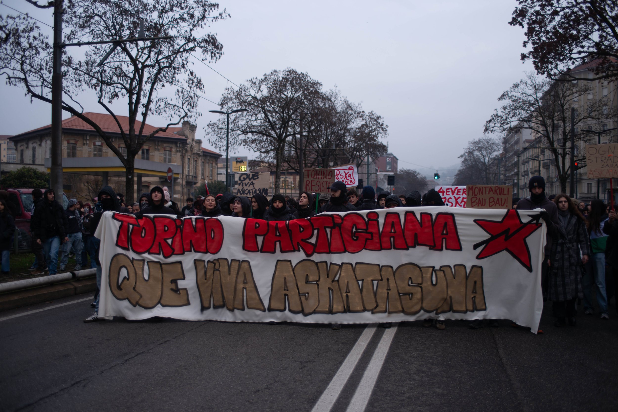 Turin, Italy – December 20, 2025: Demonstrators march behind a large banner referencing the city’s partisan heritage as they lead a protest against the eviction of the Askatasuna social center.