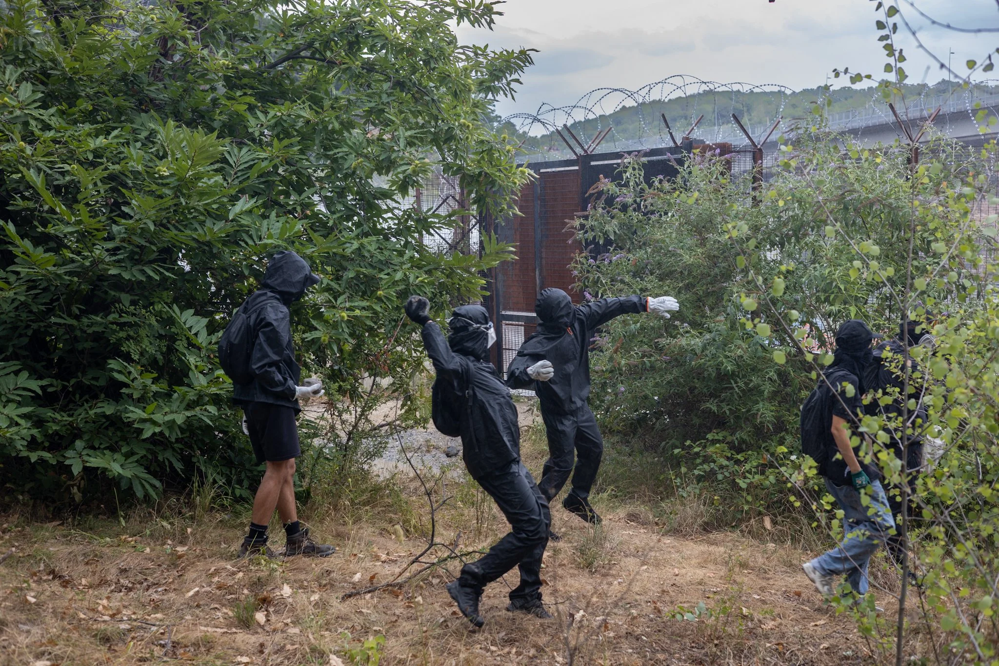 Chiomonte, Italy – July 25, 2026: No Tav protest: Black Bloc members throwing stones from outside the gate of the Chiomonte construction site