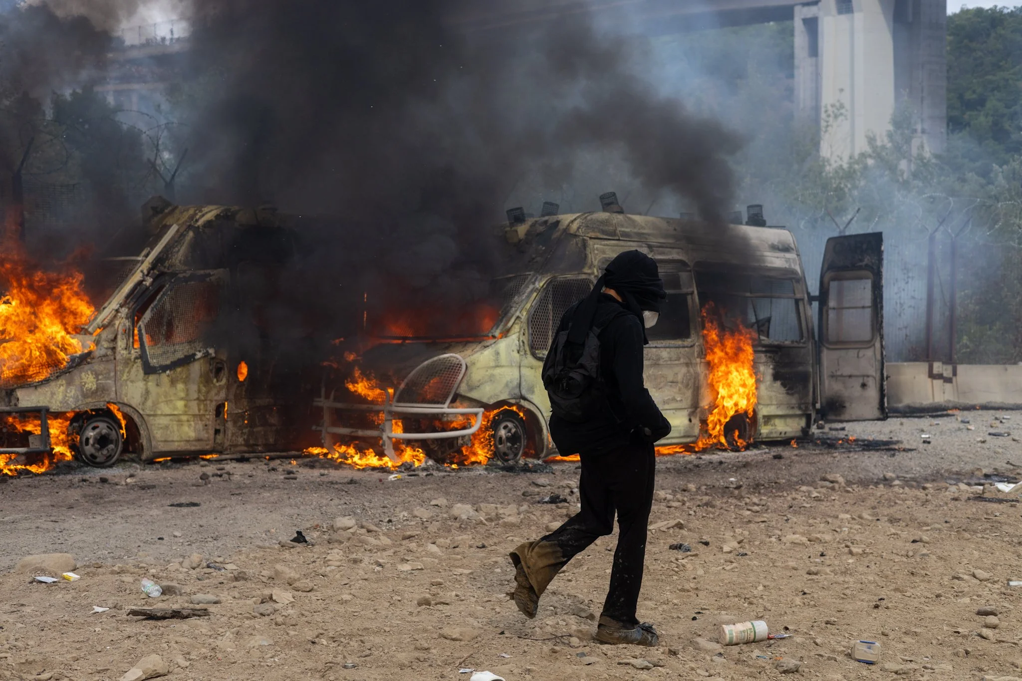 Chiomonte, Italy – July 25, 2026: No Tav protest: No Tav protest, Black bloc walking in front of burning Carabinieri vans