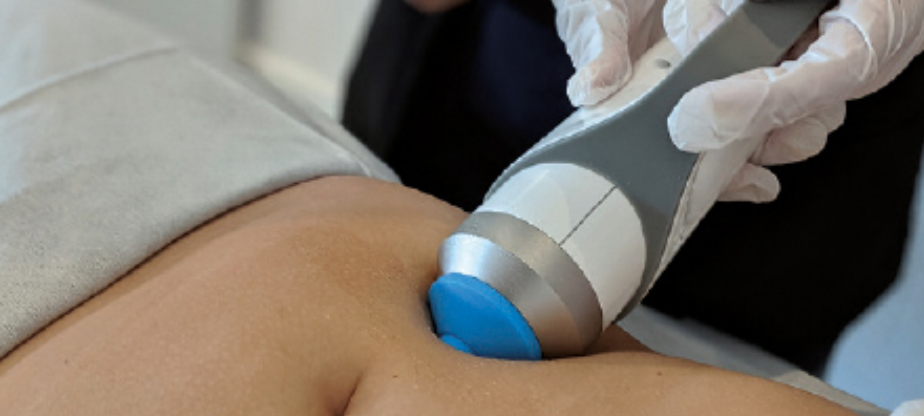 Medical professional using ultrasound or similar device on patient's abdomen.