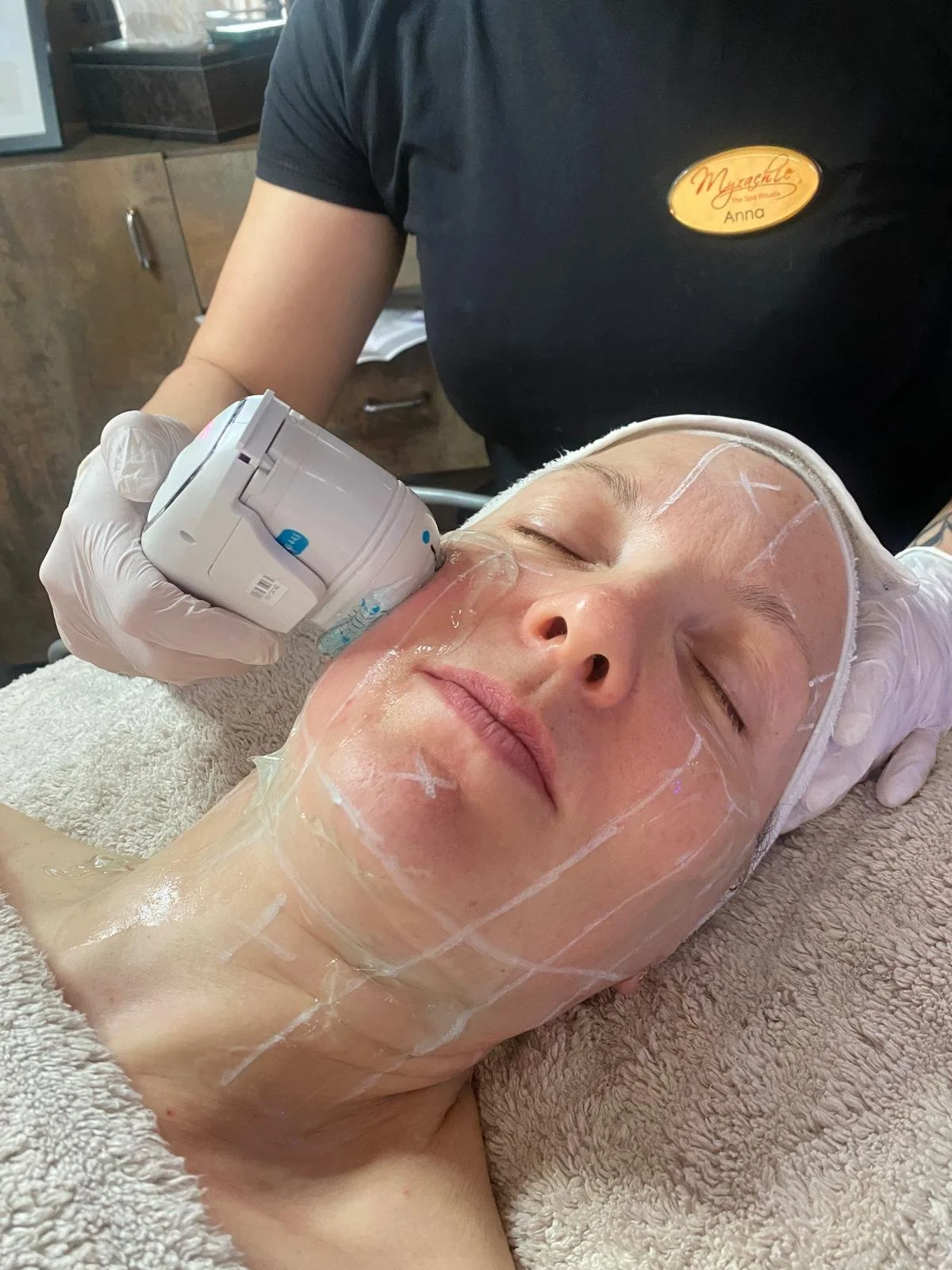 Woman receiving a facial treatment with a device on her face in a skincare clinic
