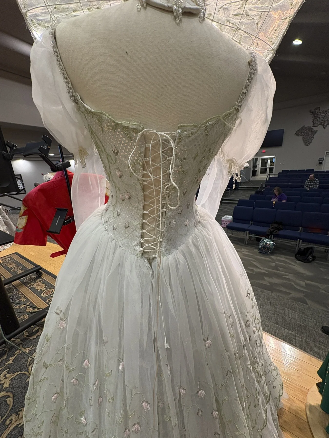 Back view of the gown revealing a corset-style lacing and flowing layered skirt that add elegance and theatrical flair.