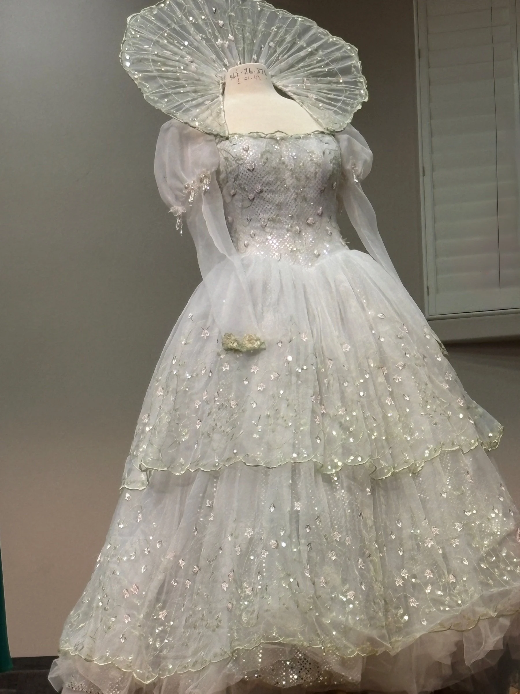 Glenda the Good Witch gown created for actress Georgia Engel (Esmeralda), featuring ethereal fabrics, shimmering embellishments, and a dramatic fairytale collar inspired by Wicked.